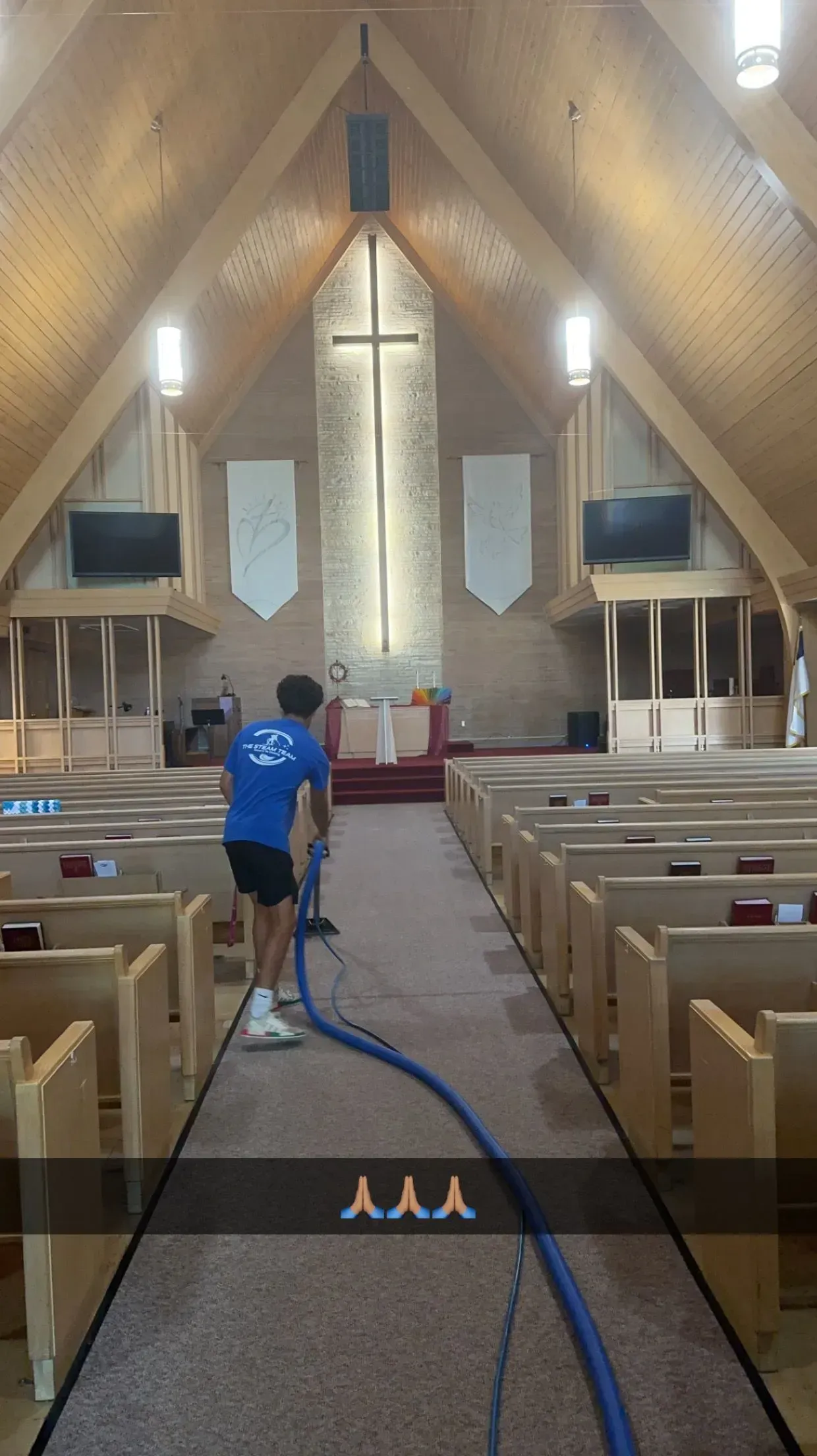 A man is cleaning the carpet in a church with a vacuum cleaner.