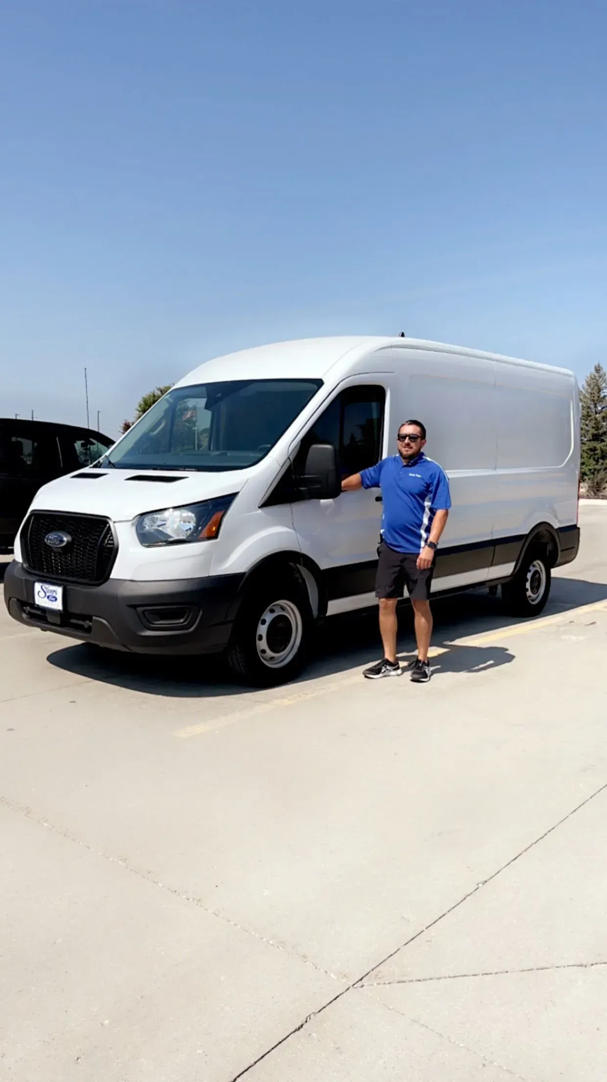 A man is standing in front of a white van.