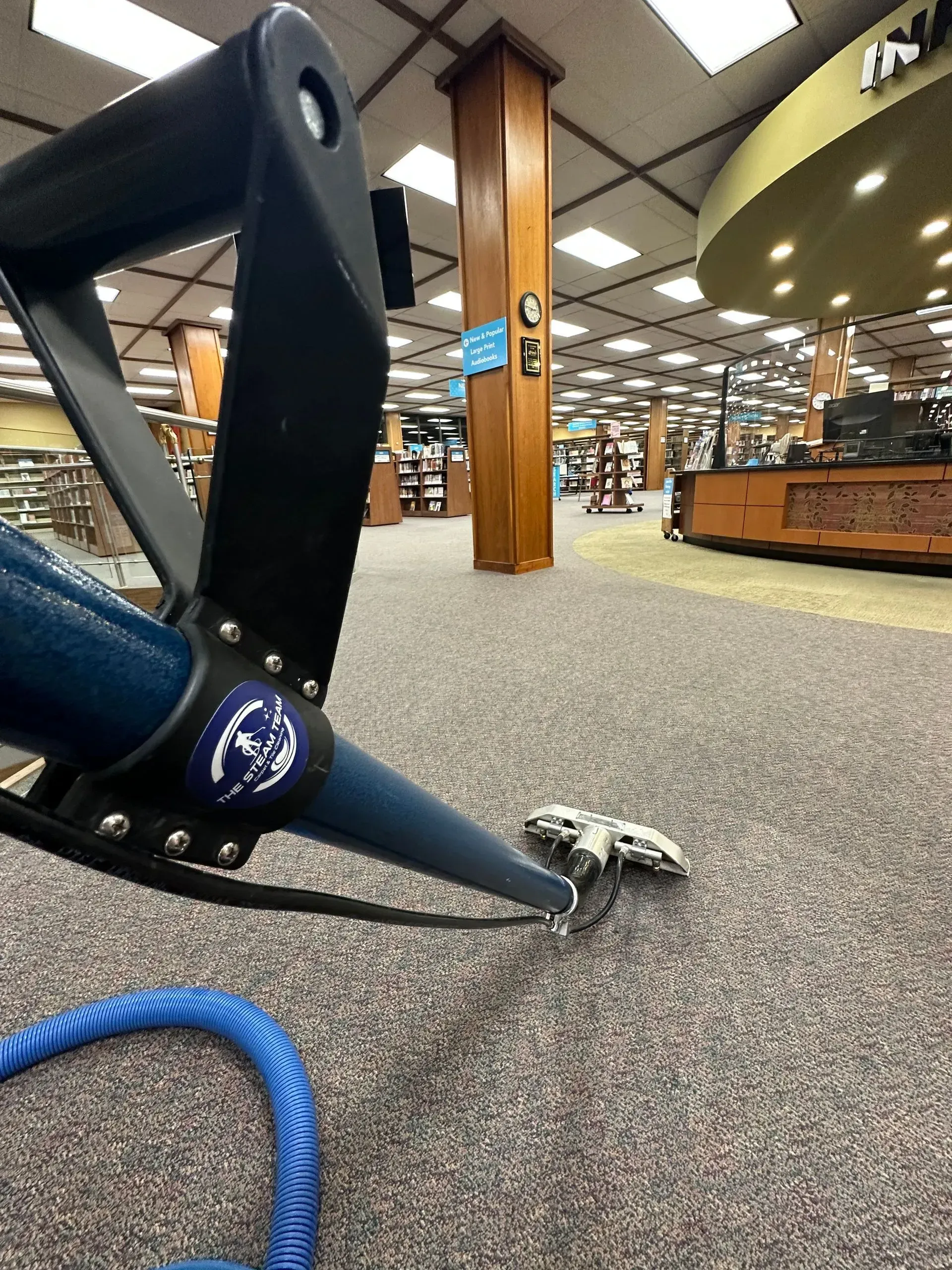 A vacuum cleaner is cleaning a carpet in a library.