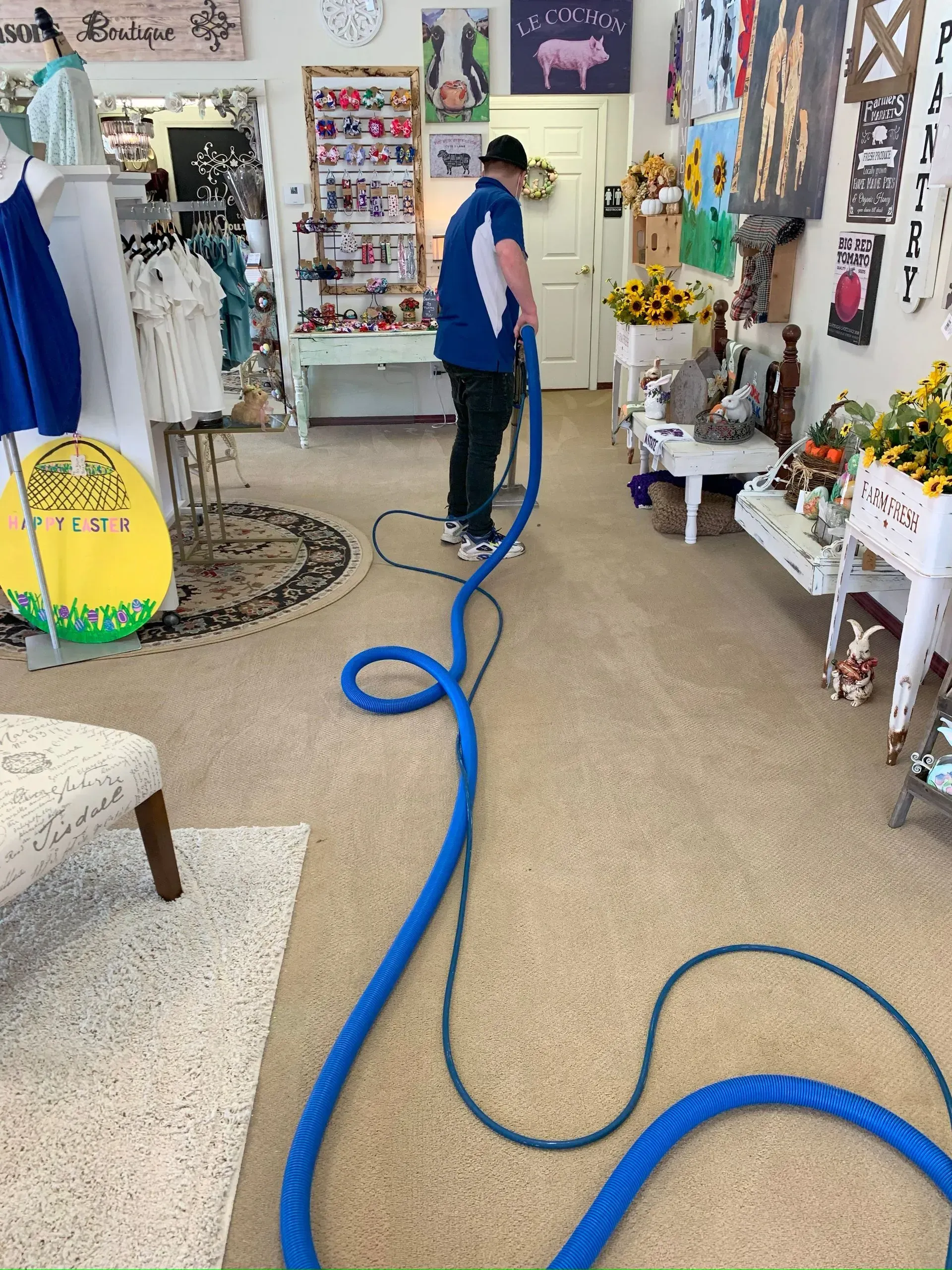A man is cleaning the floor of a store with a blue hose