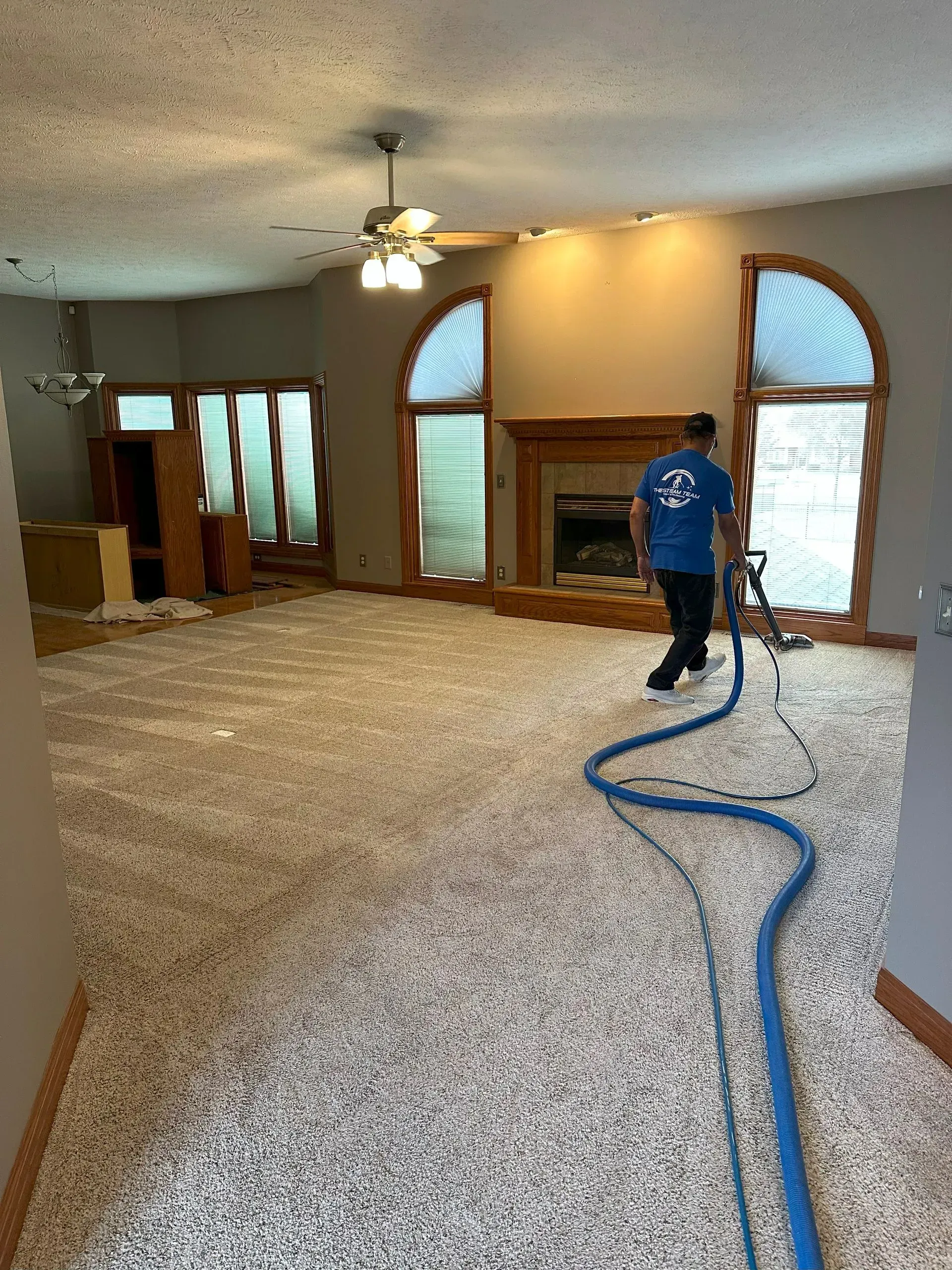 A man is cleaning a carpet in a living room with a vacuum cleaner.