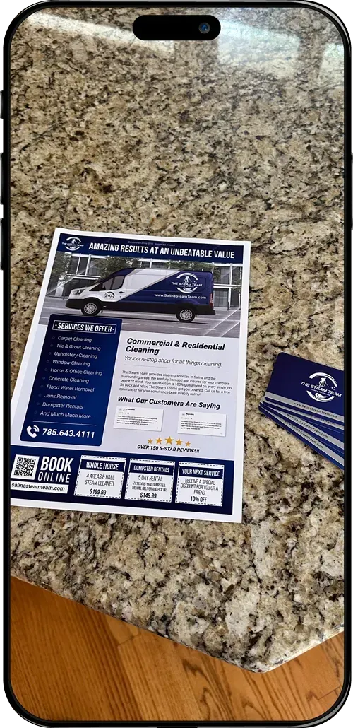 A cell phone is sitting on a counter next to a piece of paper and a business card.