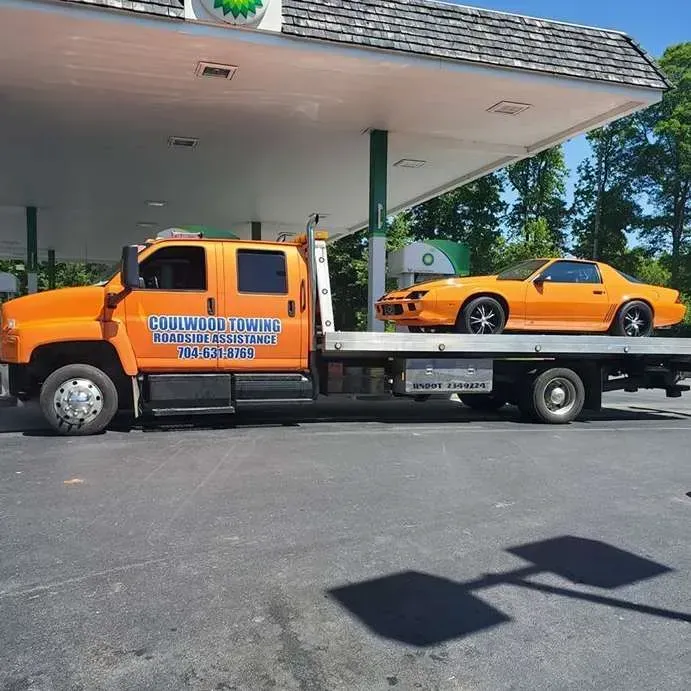 Orange tow truck with orange sports car at a BP gas station.