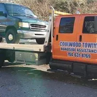 Tow truck towing a green van; orange tow truck with Coulwood Towing logo.