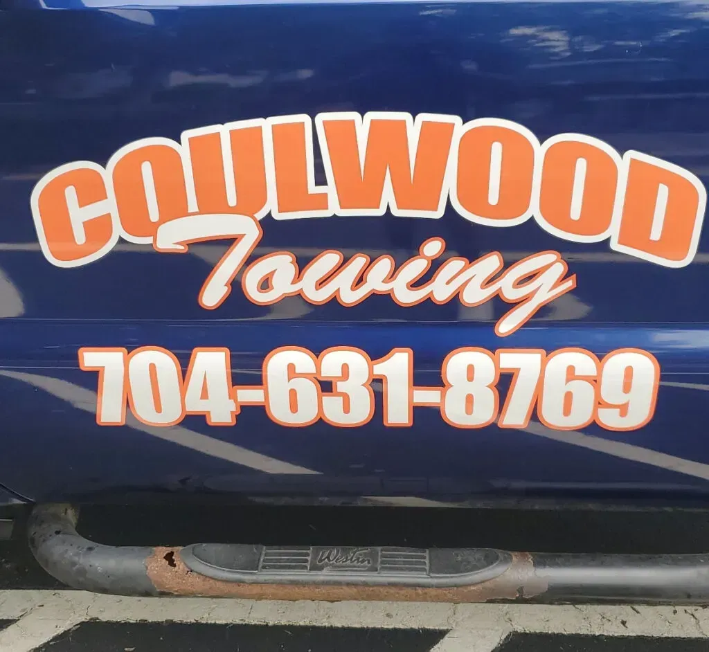 Coulwood Towing logo on a blue truck door: orange text outlined in white, phone number 704-631-8769.