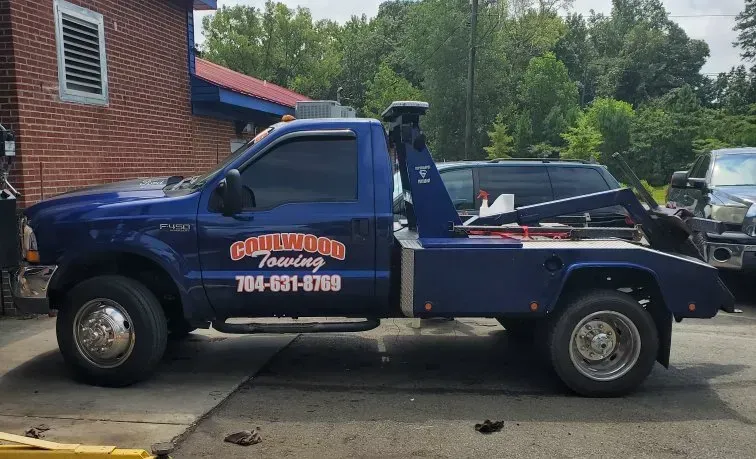Blue tow truck parked in front of a building; 