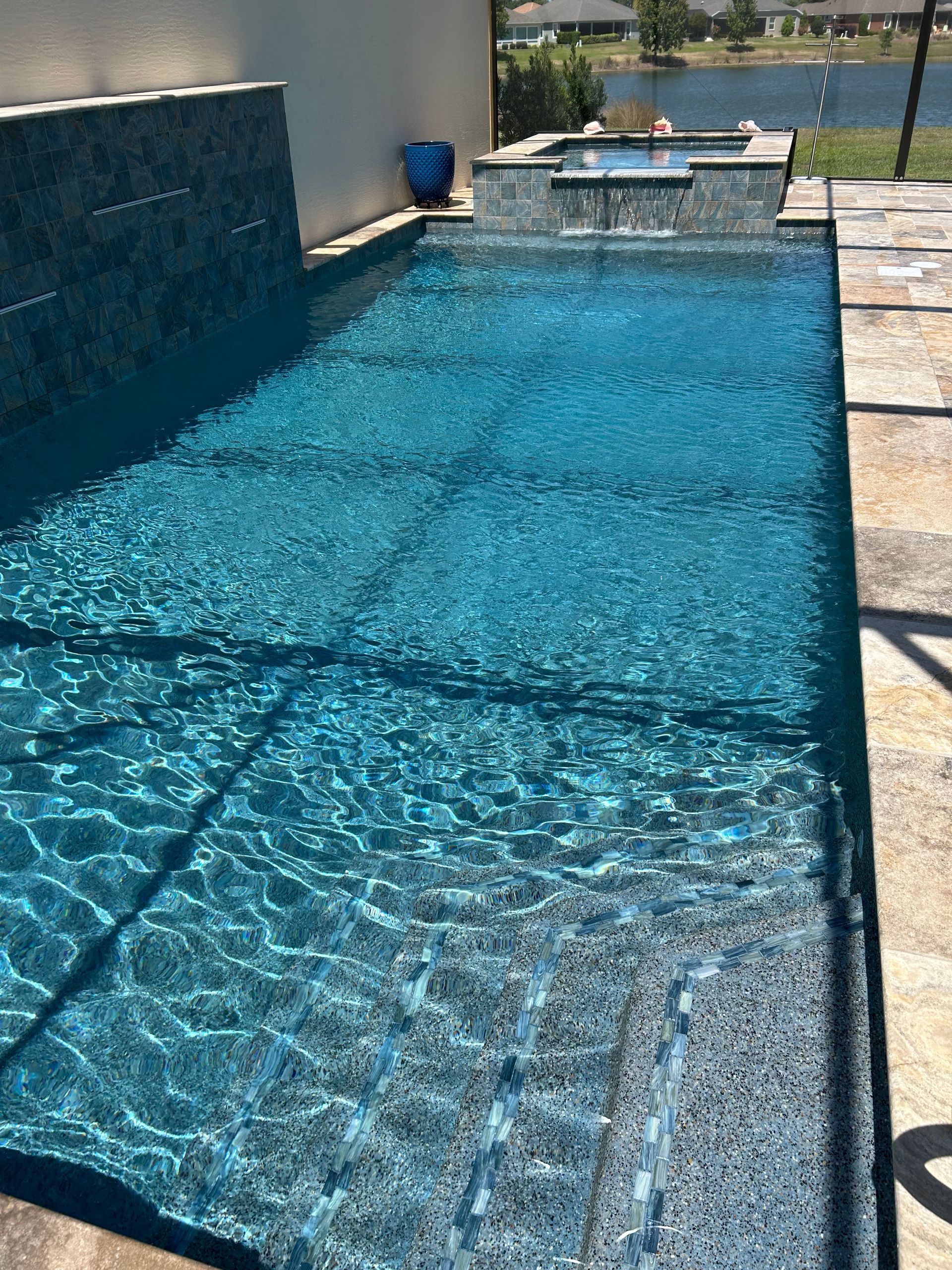 A large swimming pool filled with blue water and a waterfall.