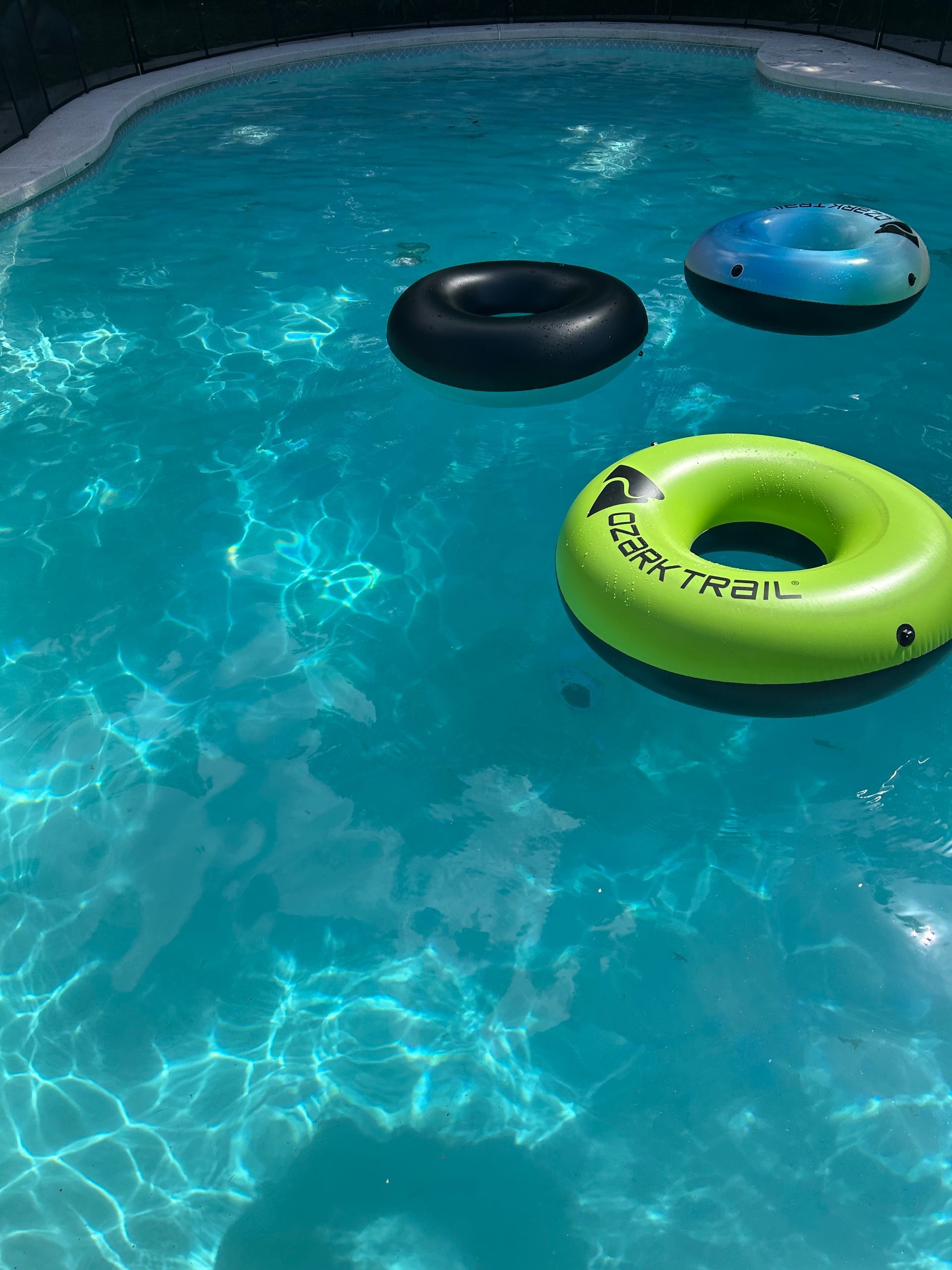 Three floats in a pool one of which says trail on it