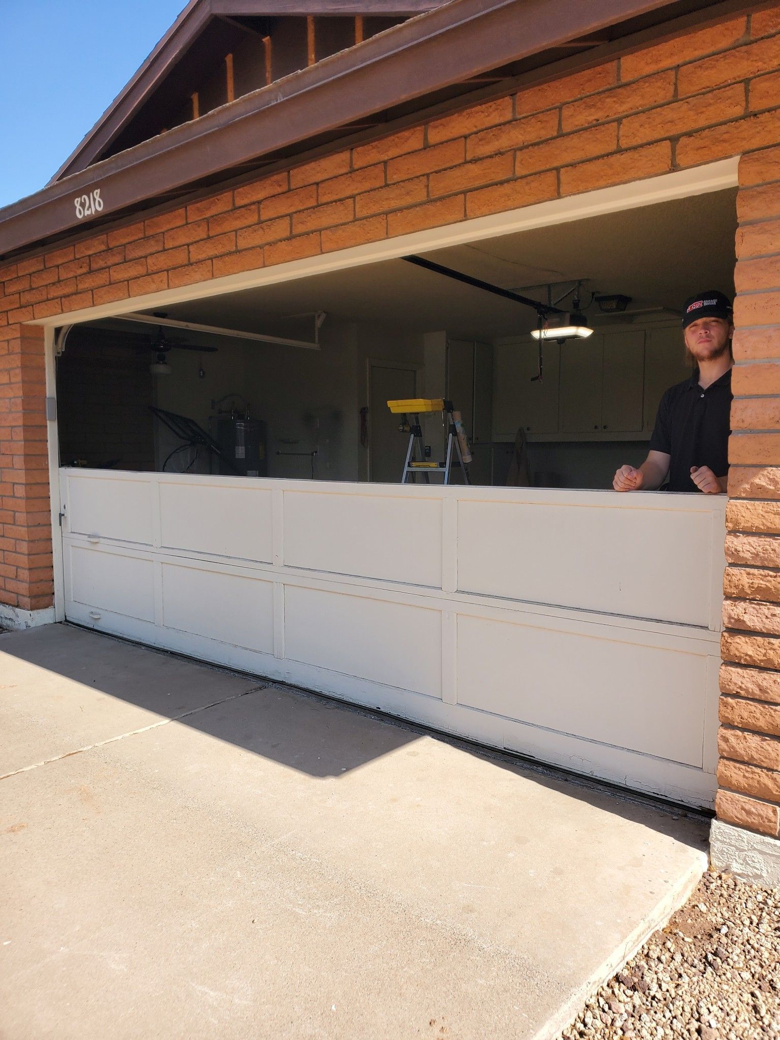 A man is standing in a garage with the door open.