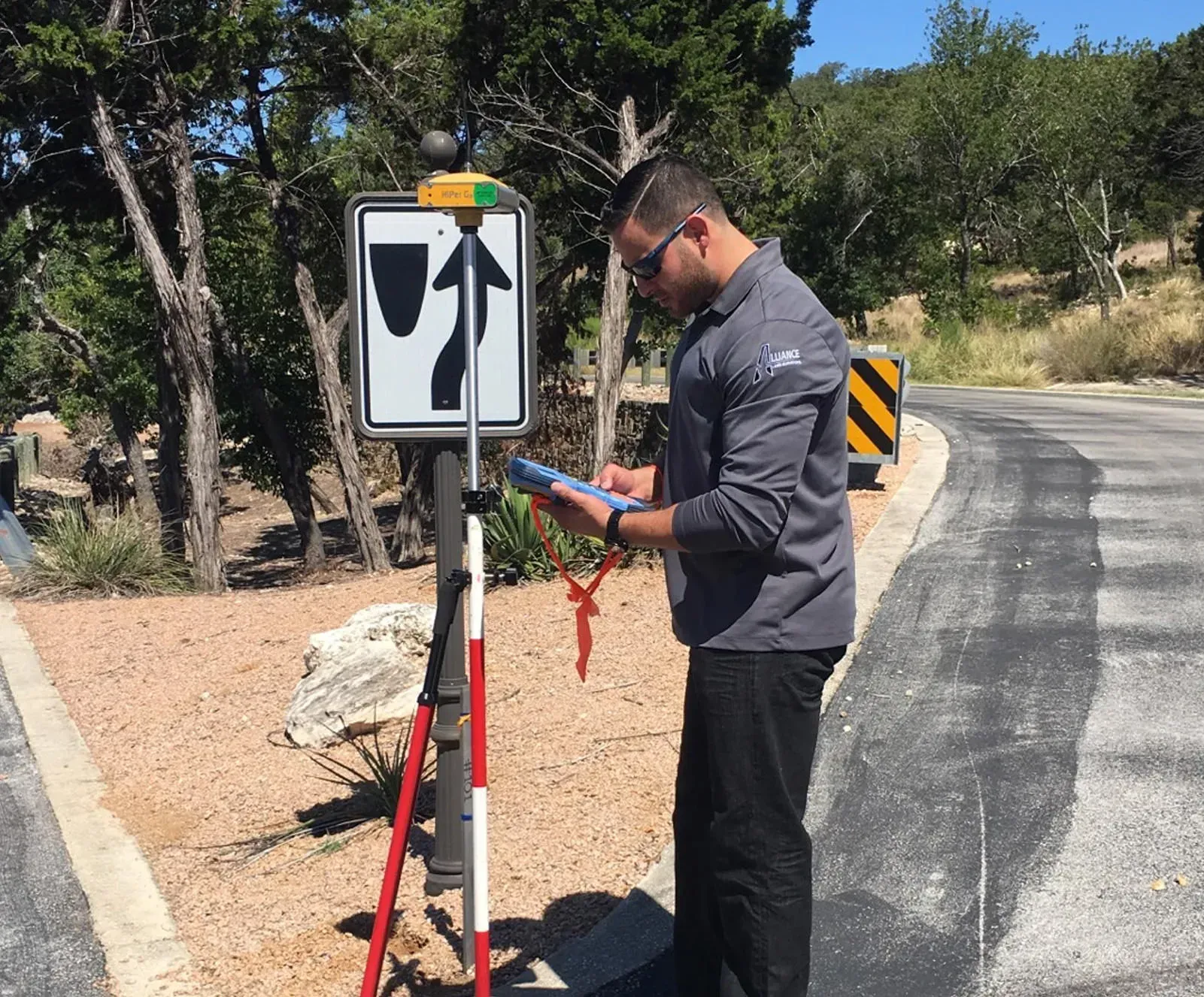 Land surveyor from Alliance Land Surveyors CEO working with surveying equipment on a roadside in San Antonio, Texas.