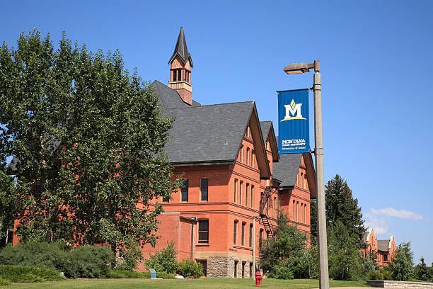 Brick building with a dark roof and a small tower; Montana State University banner in the foreground.
