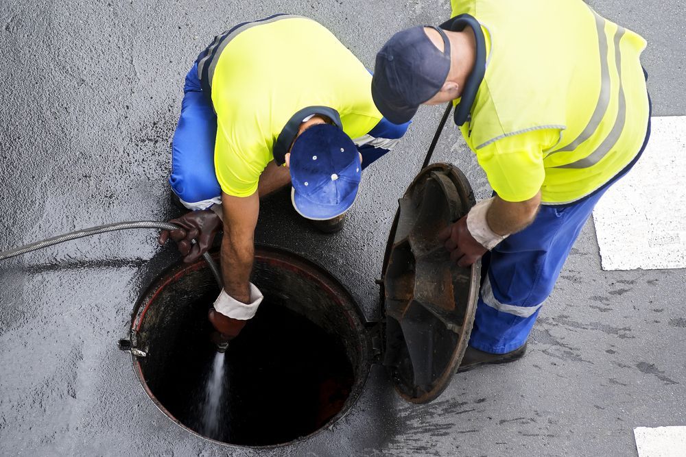 Two men are working on a manhole cover.