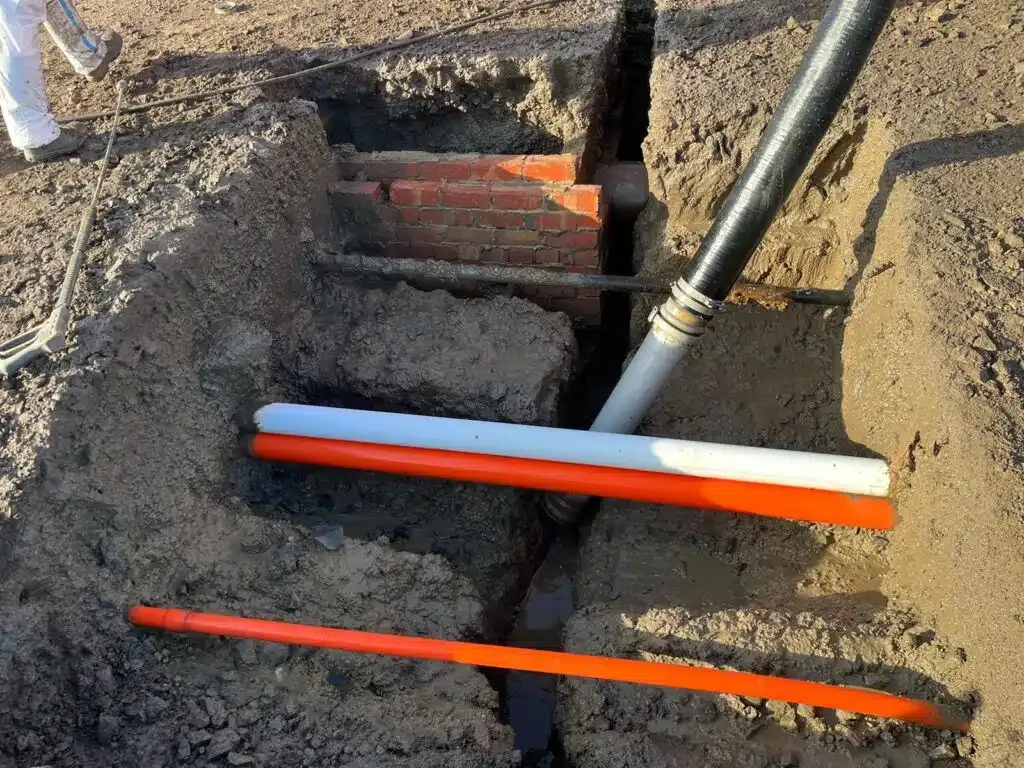 A bunch of pipes are laying in the dirt