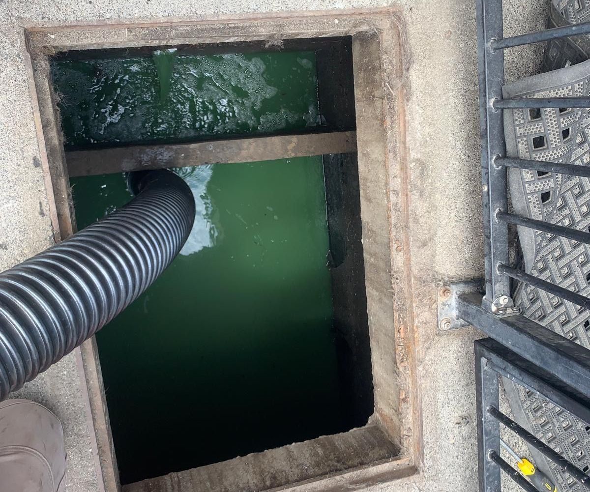 A manhole cover is being cleaned with a hose.