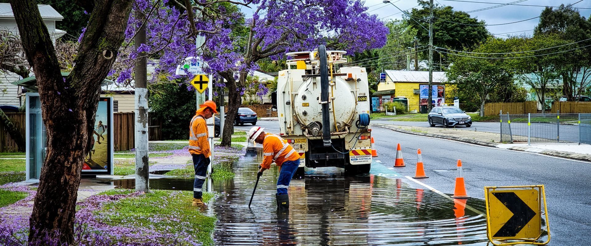 A group of men are cleaning a flooded street with a truck.