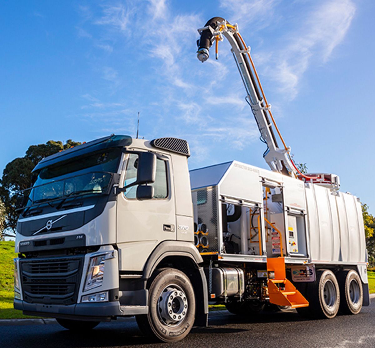 A white truck with a crane on the back is parked on the side of the road.