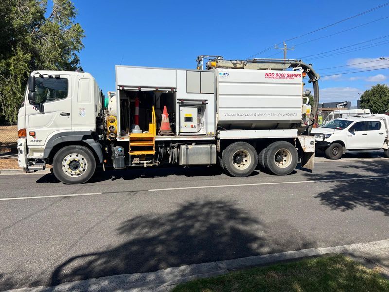 A blue truck is parked in a parking lot next to a traffic cone.