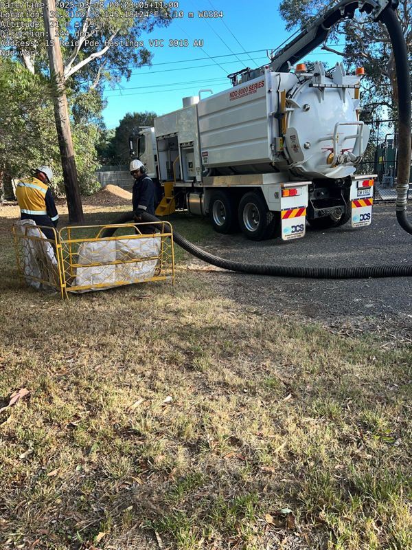 A man is standing in front of a yellow vacuum truck
