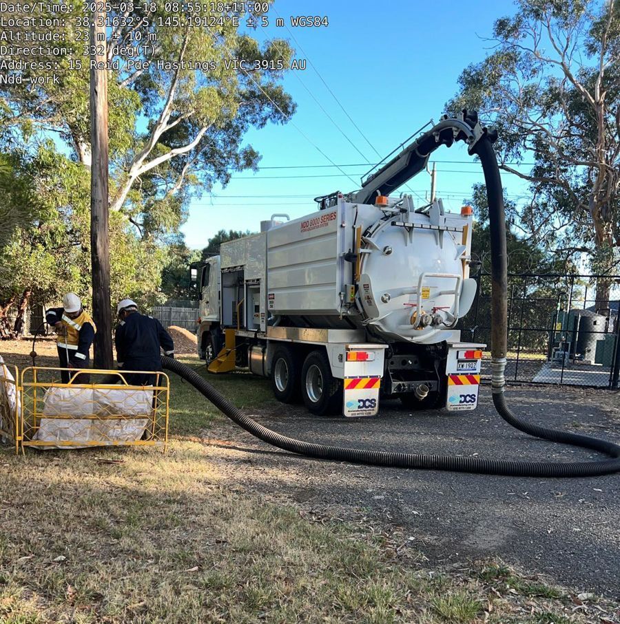 A vacuum truck is parked on the side of the road