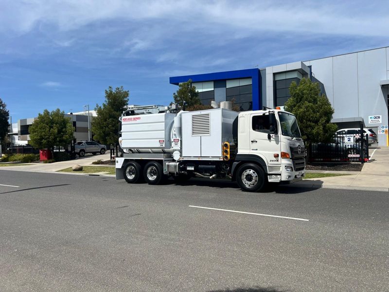 A yellow vacuum truck is parked on the side of the road.