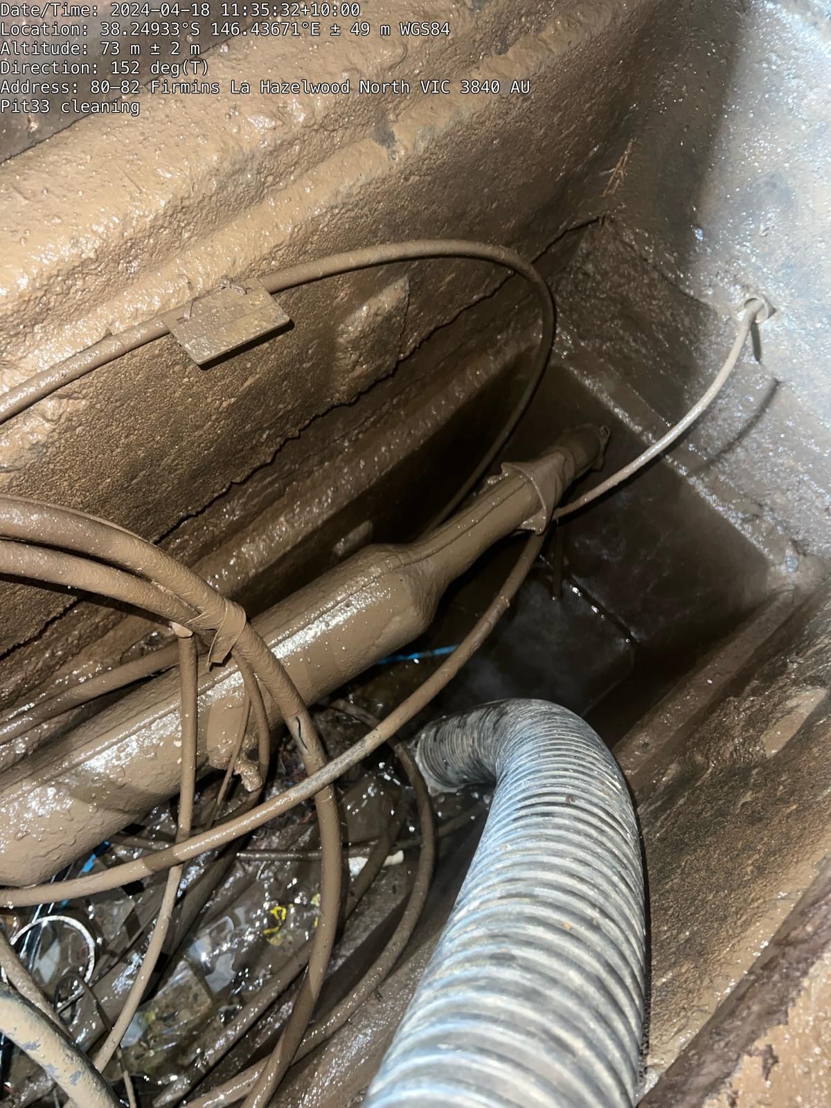 A hose is connected to a pipe in a dirty room.