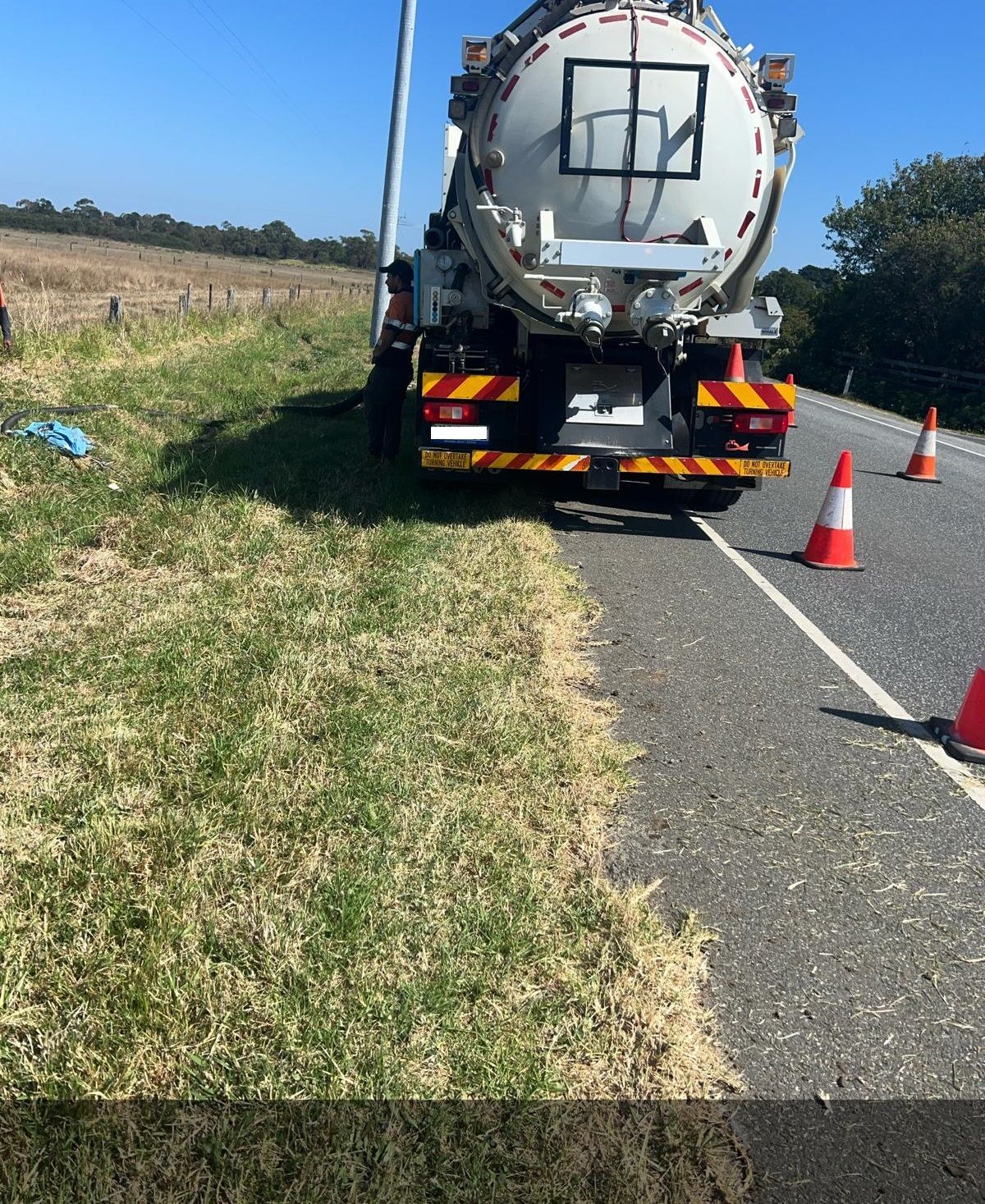A vacuum truck is parked on the side of the road.