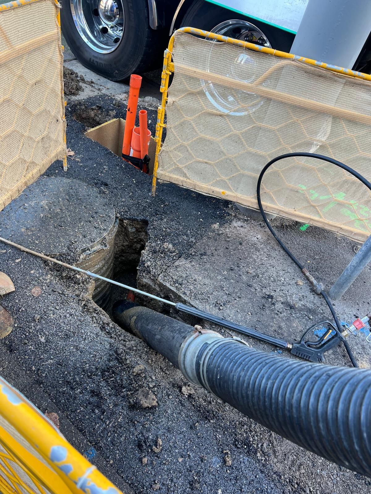 A hose is being used to pump water into a hole in the ground.