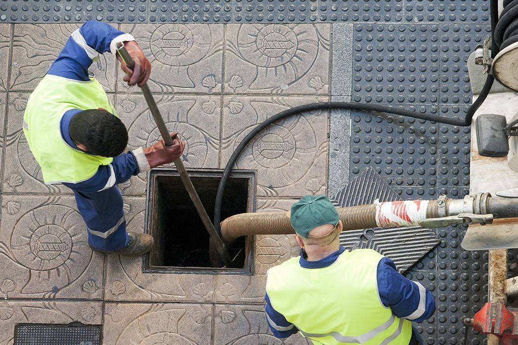 Two men are working on a manhole cover.