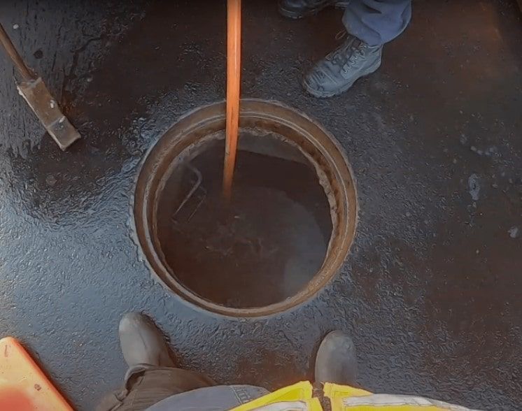 A manhole cover is being cleaned with a hose.