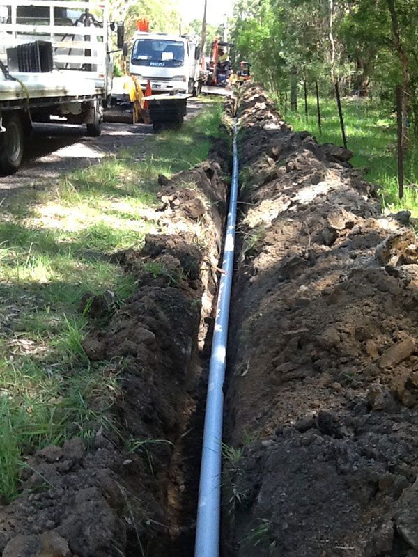 A pipe is being installed in the dirt next to a truck
