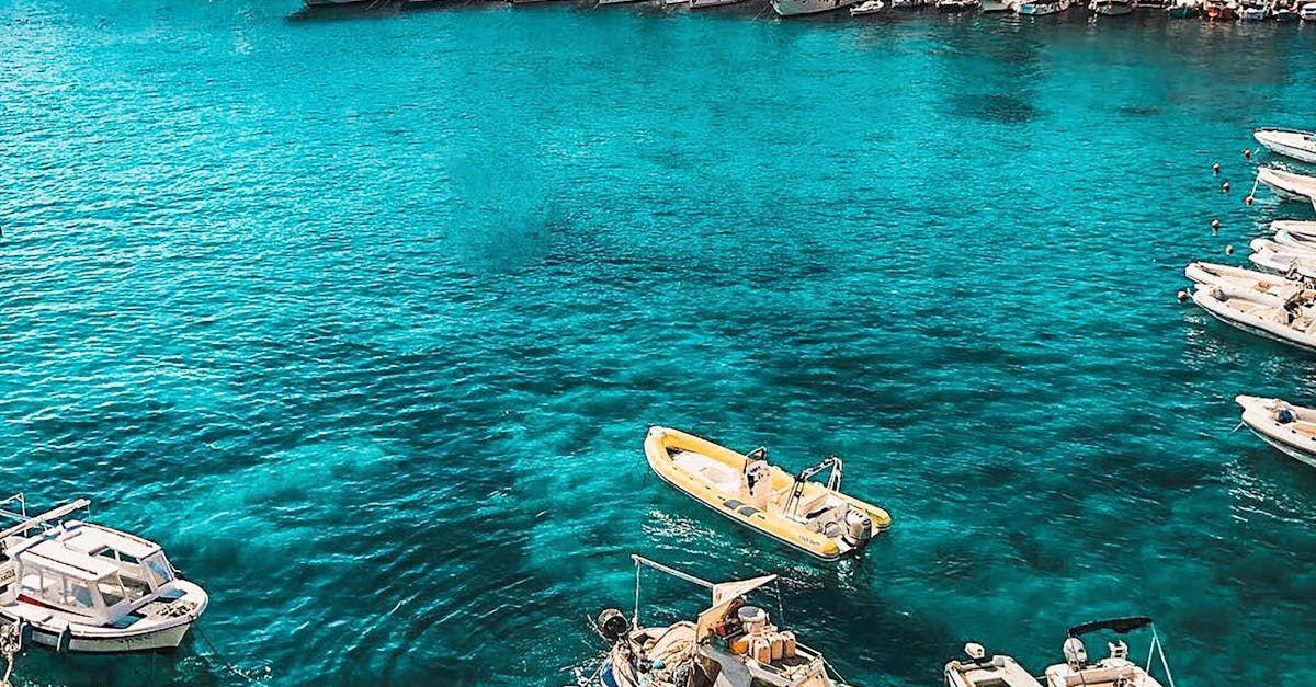 Aerial view of turquoise water with several boats and yachts in a busy harbor