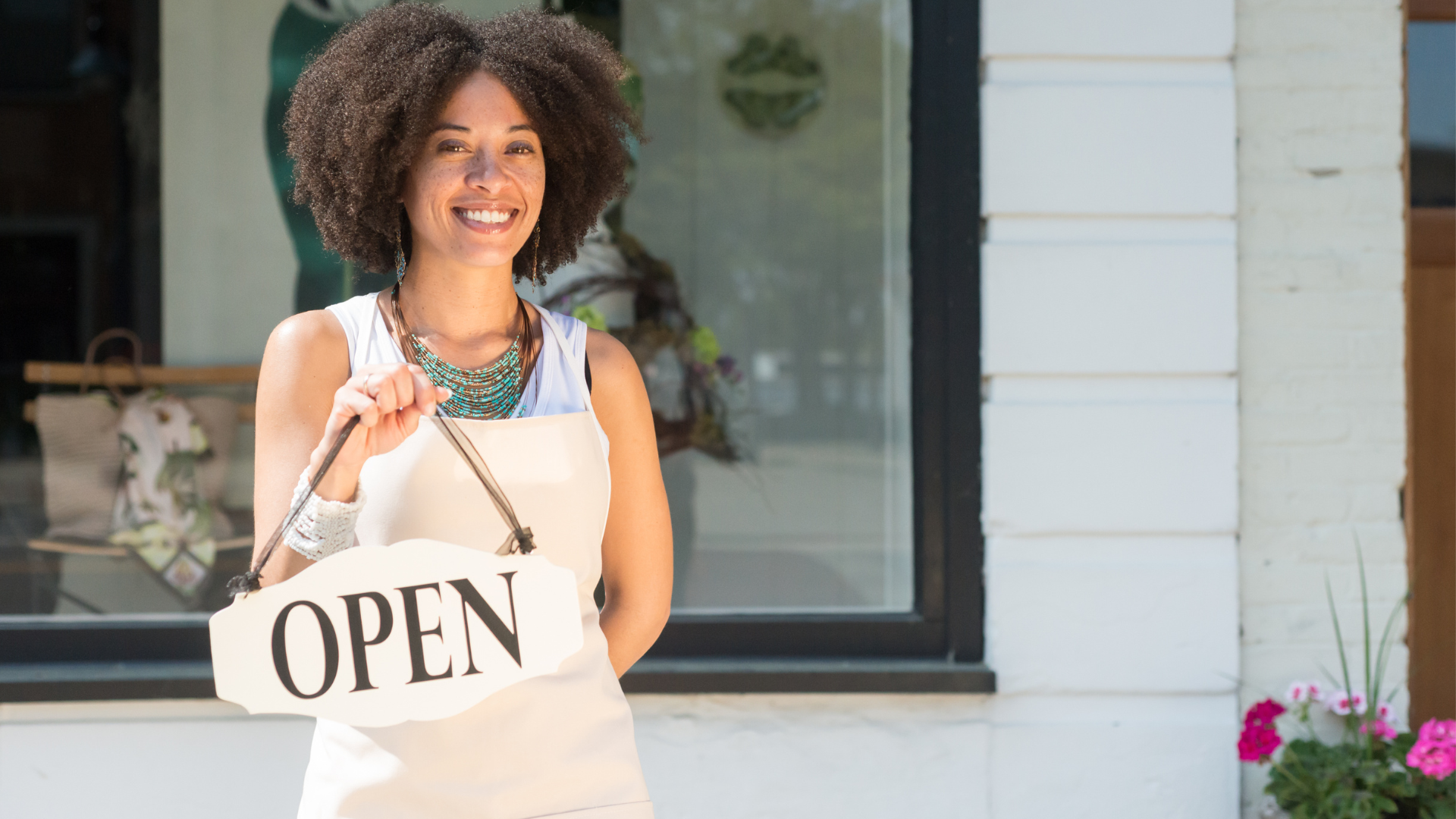 a woman is holding an open sign in front of a store .