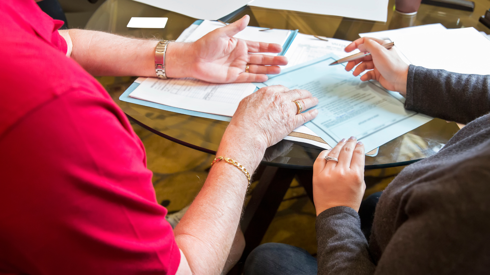 a man and a woman are sitting at a table looking at papers .