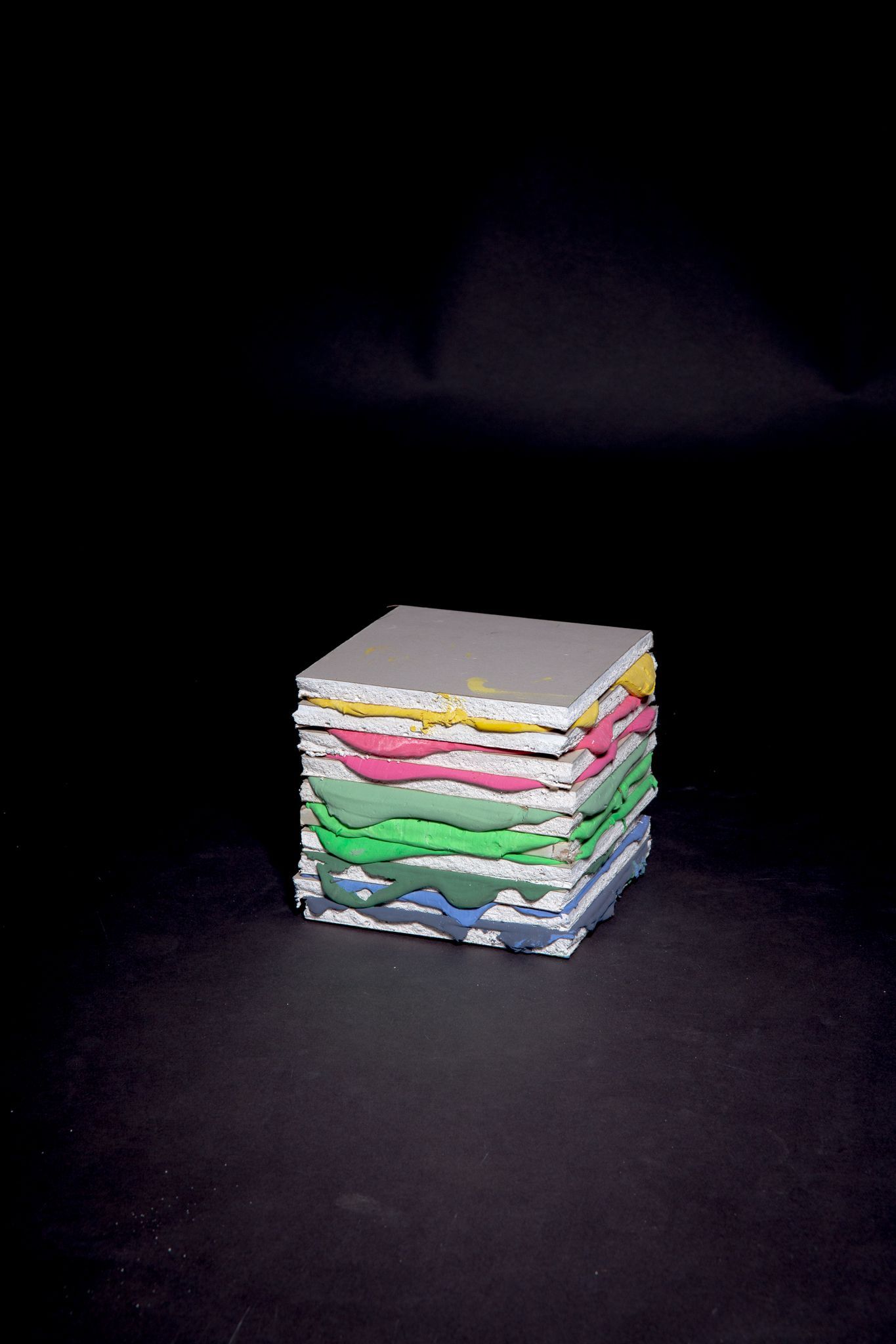 Stacked colorful paper squares in front of a dark background, forming a cube shape; art by Matt Remsbecher. 