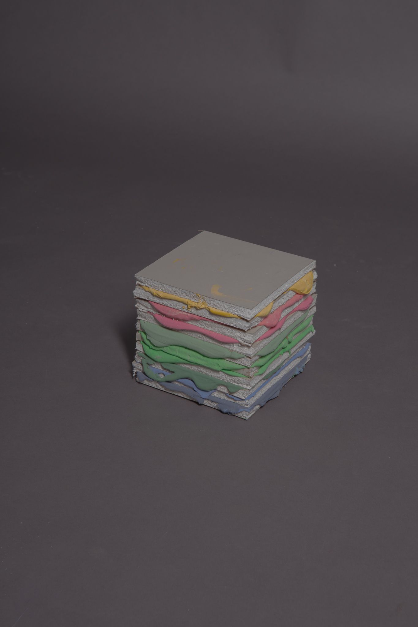 Stack of colorful, textured, rectangular blocks against a gray background; art by Matt Remsbecher. 
