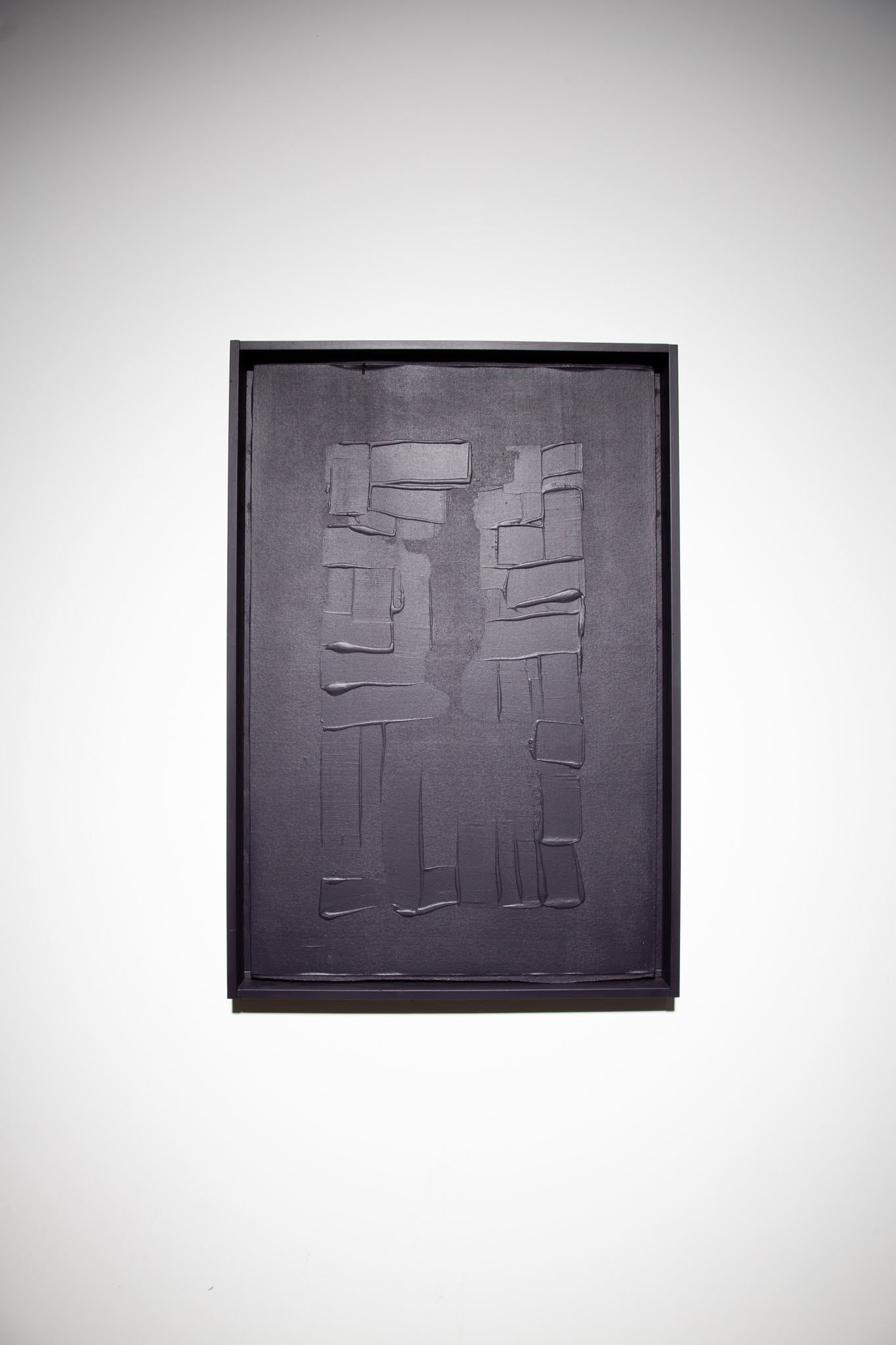 Black textured rectangular artwork in a dark frame on a white wall; art by Matt Remsbecher. 
