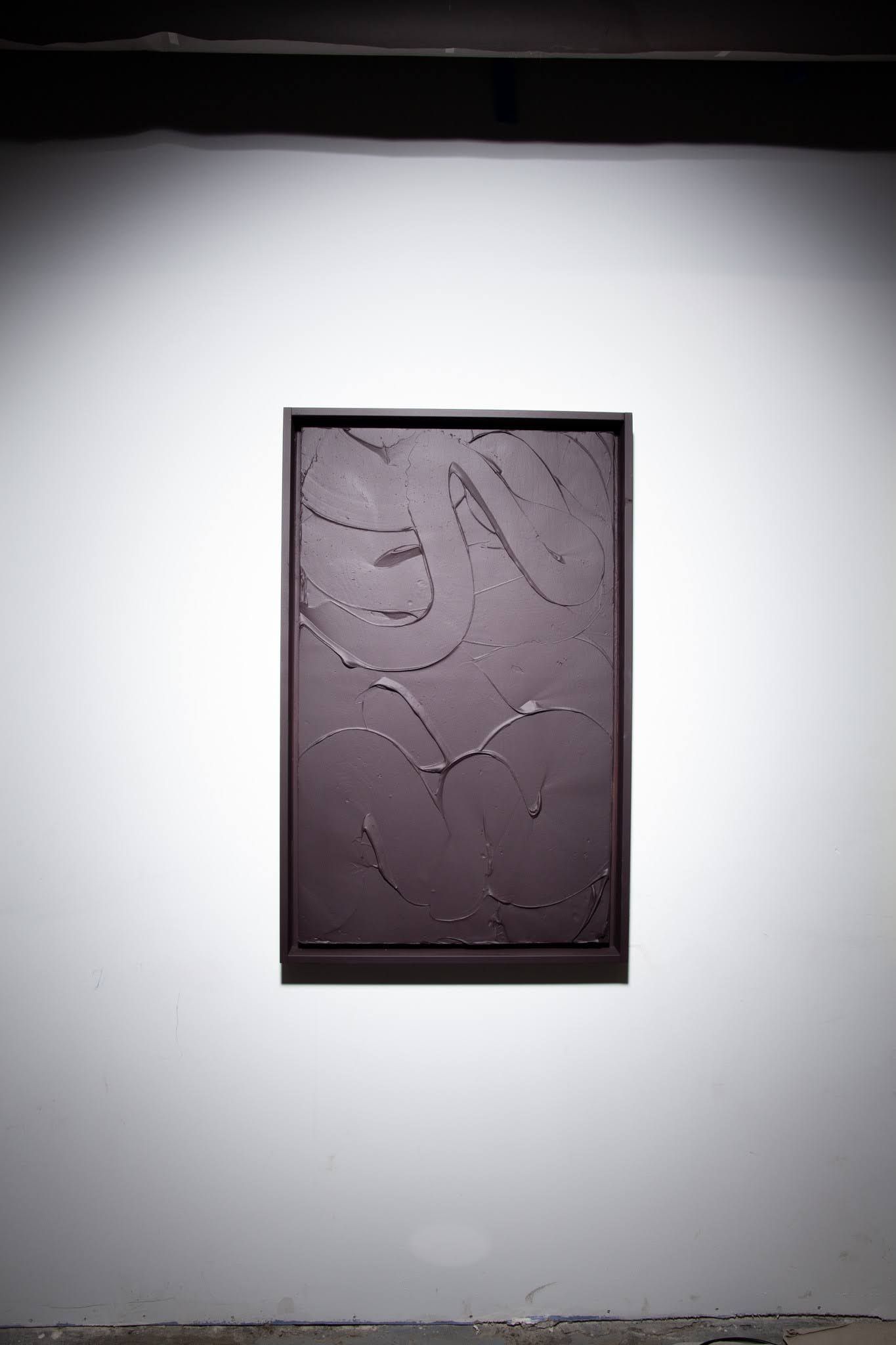 Dark, textured rectangular artwork hangs on a white wall in an art gallery; art by Matt Remsbecher. 