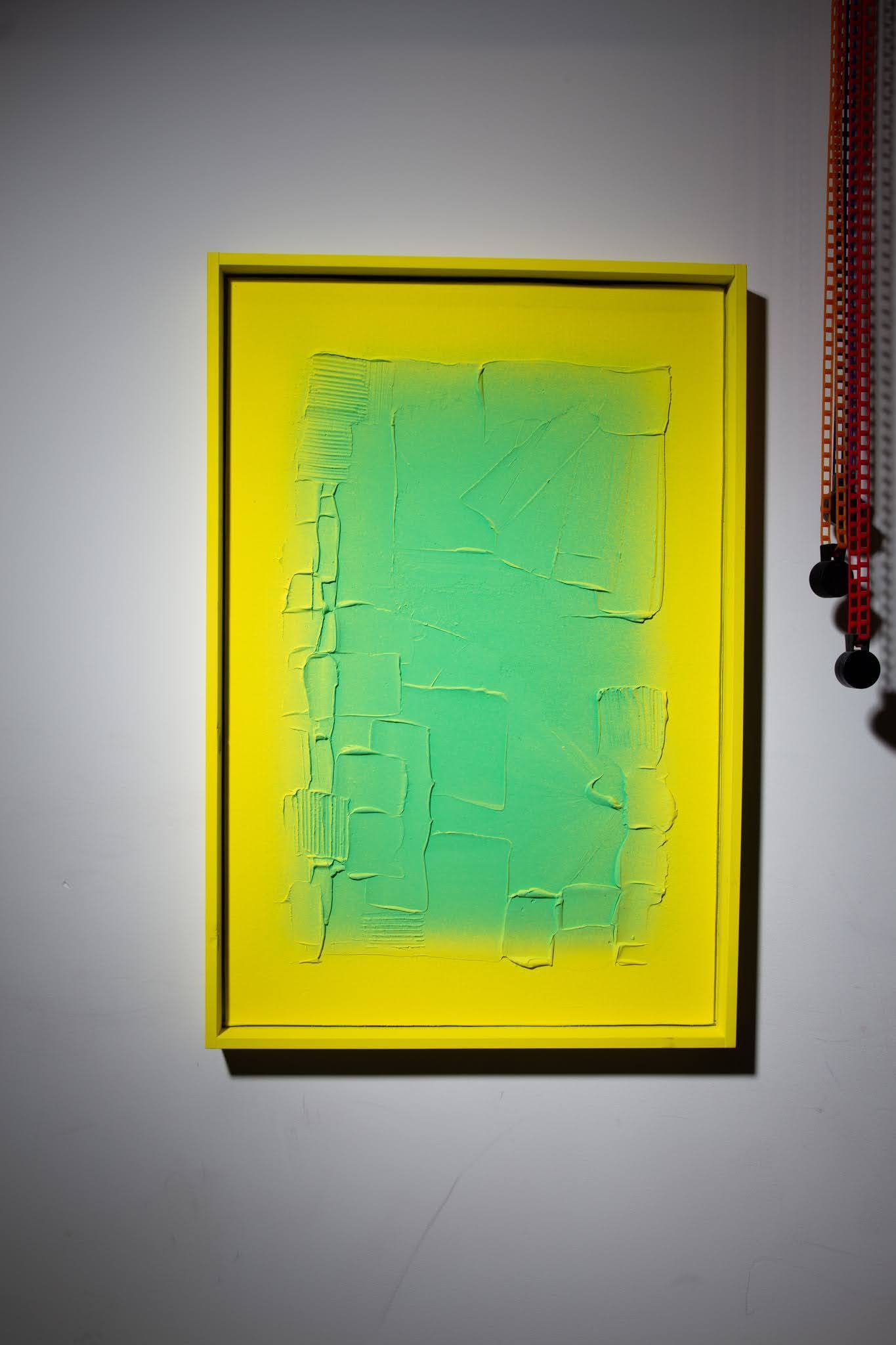 Yellow framed painting with a green center on a white wall; art by Matt Remsbecher. 