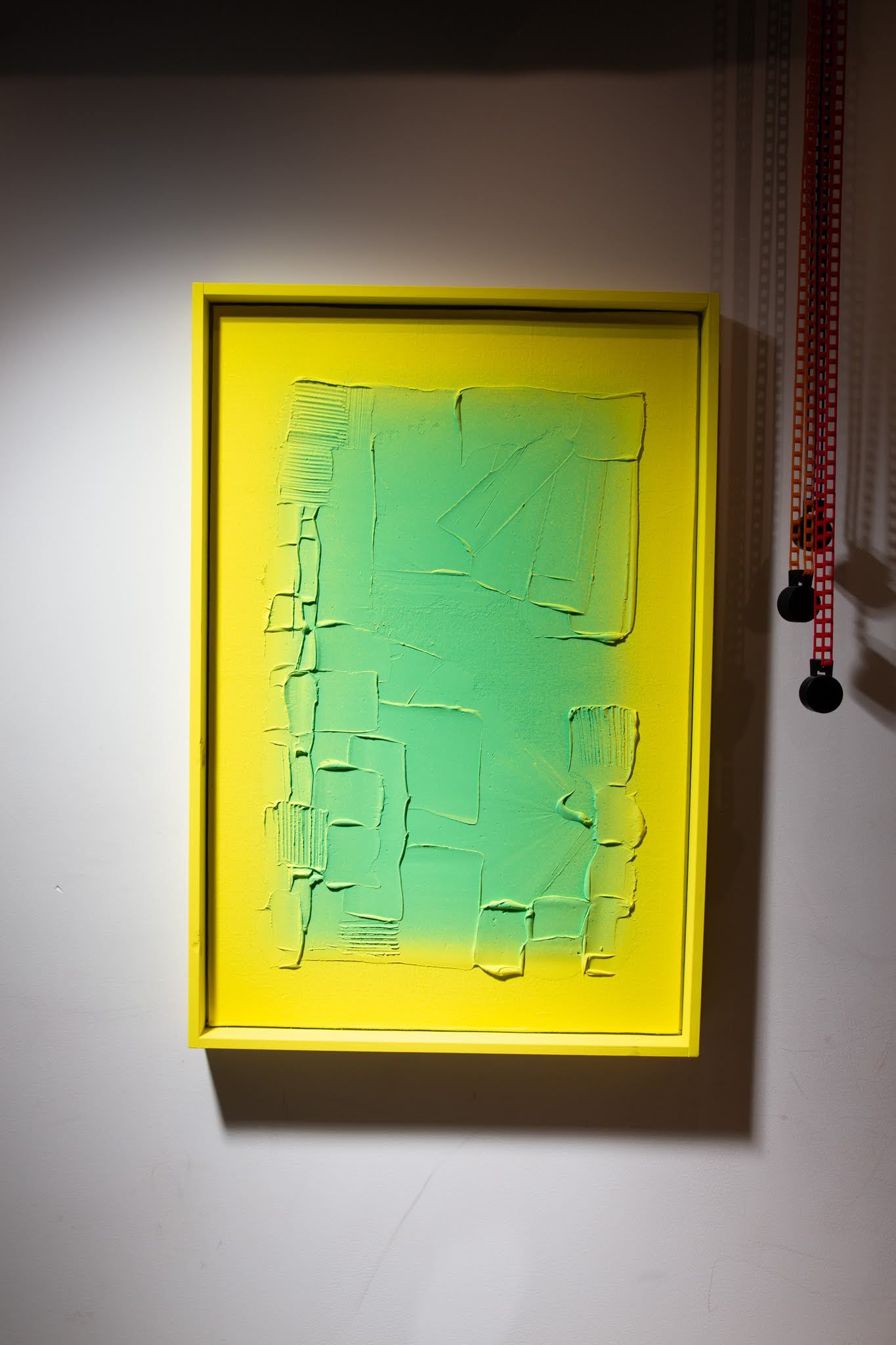 Yellow framed artwork with green textured rectangle on a white wall; art by Matt Remsbecher. 