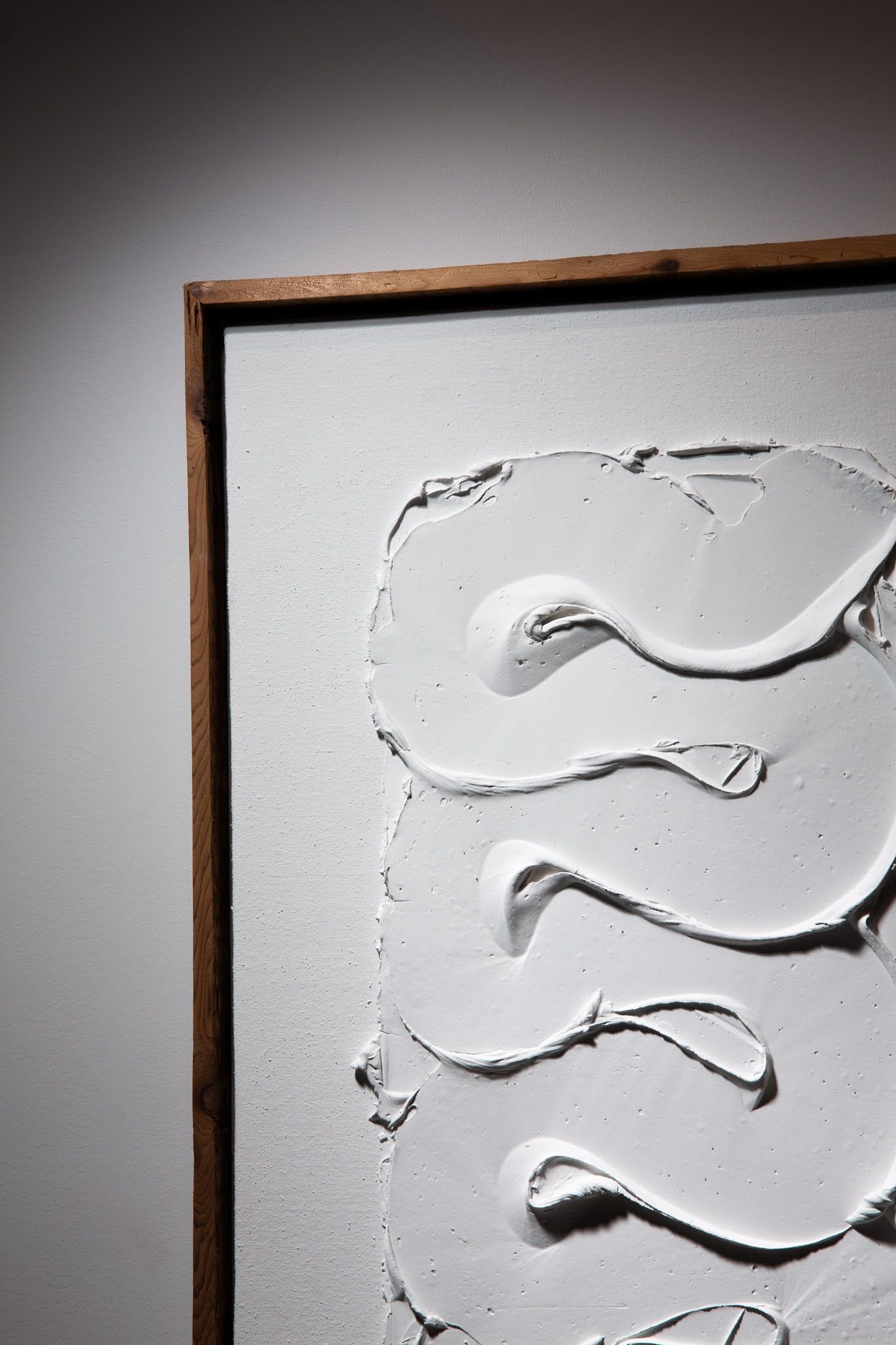 White textured artwork in a wooden frame; swirls and curves on white background; art by Matt Remsbecher. 