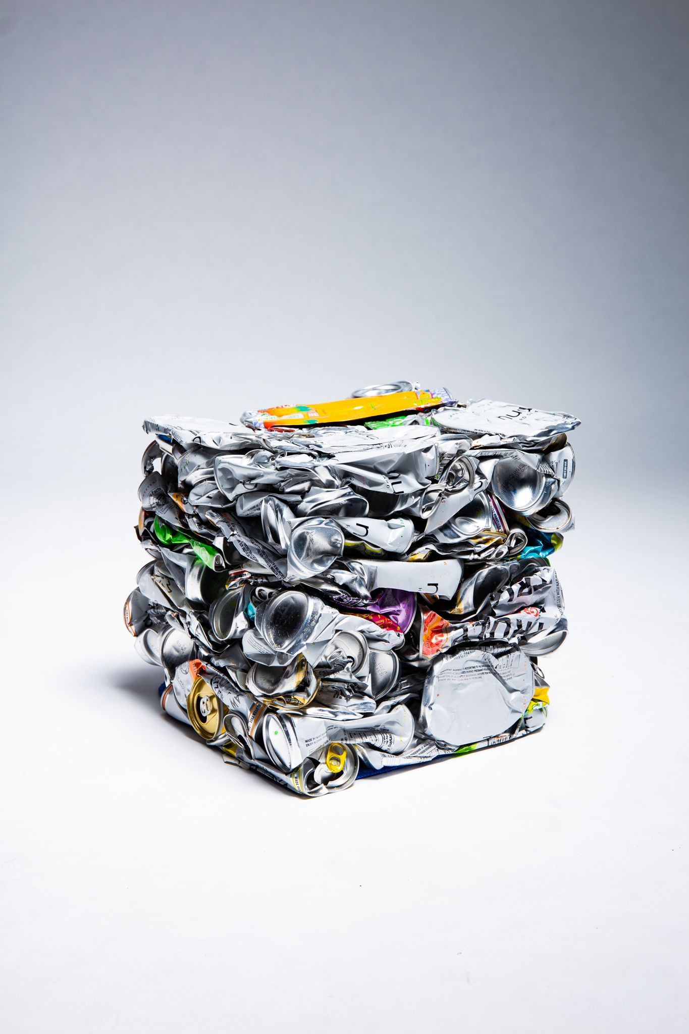 Bale of crushed aluminum cans and other recyclable materials, on a white background; art by Matt Remsbecher. 