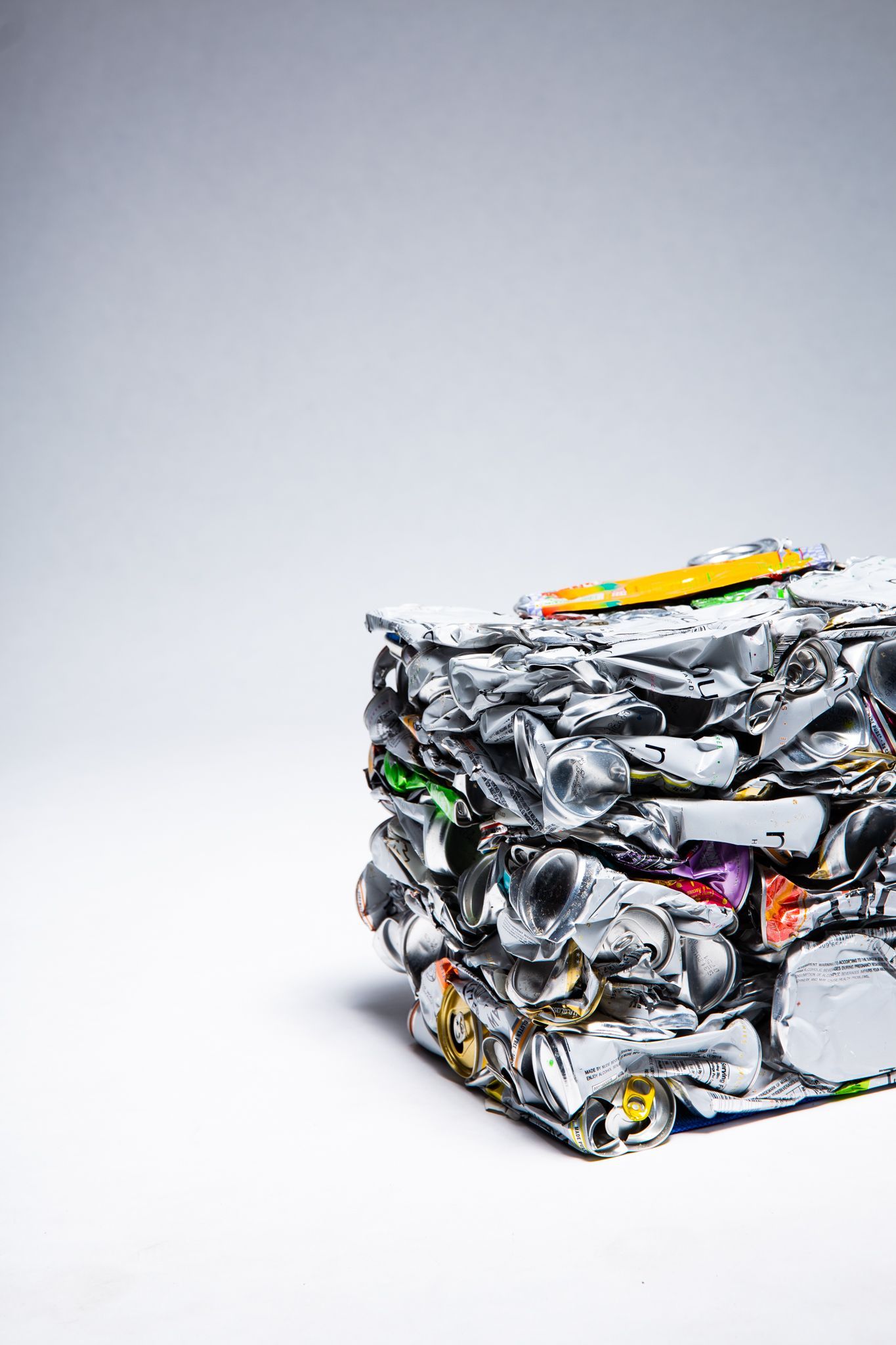 A cube of crushed aluminum cans against a white backdrop; art by Matt Remsbecher. 