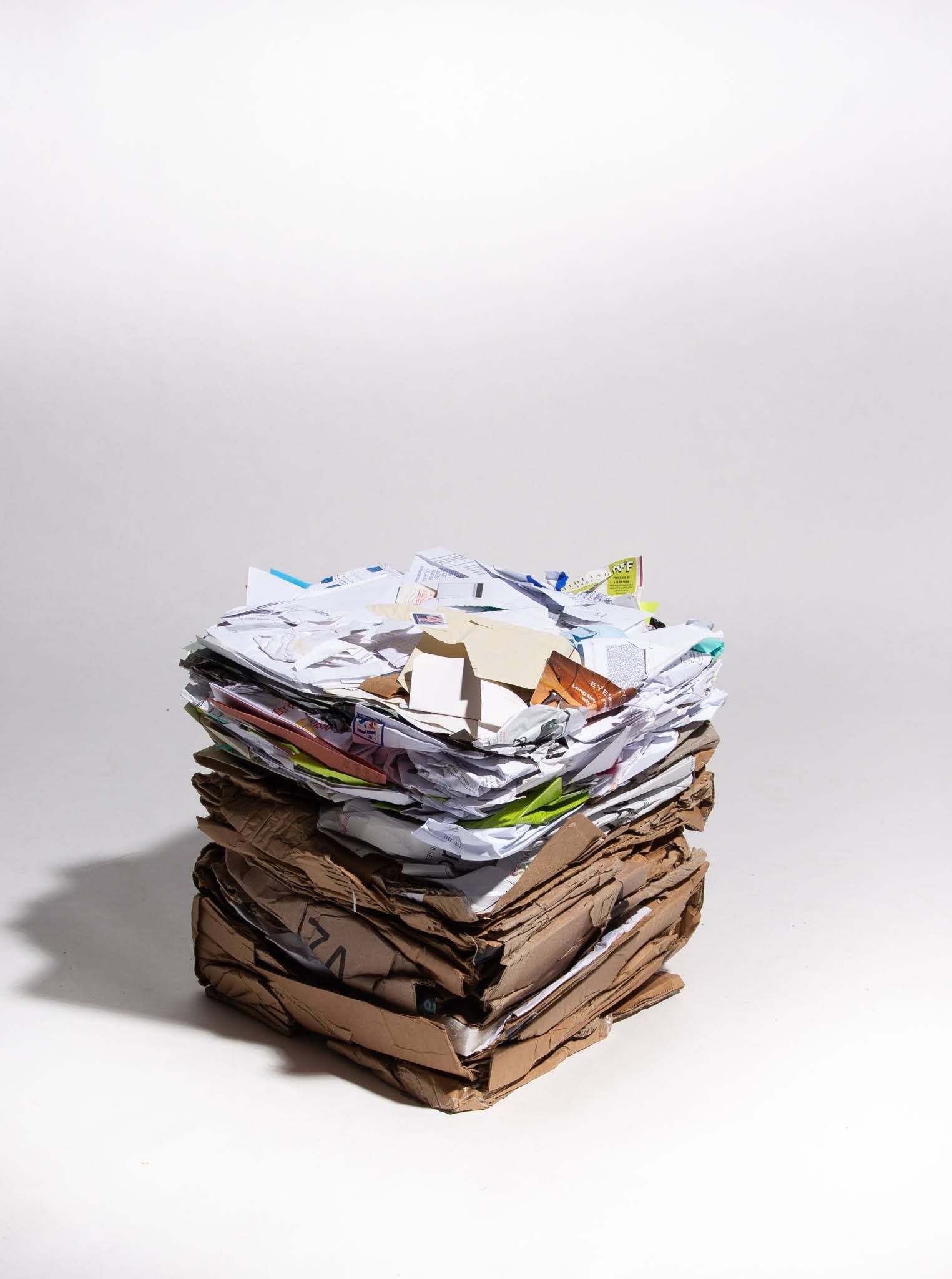 Stack of mixed paper and cardboard waste against a white background; art by Matt Remsbecher. 