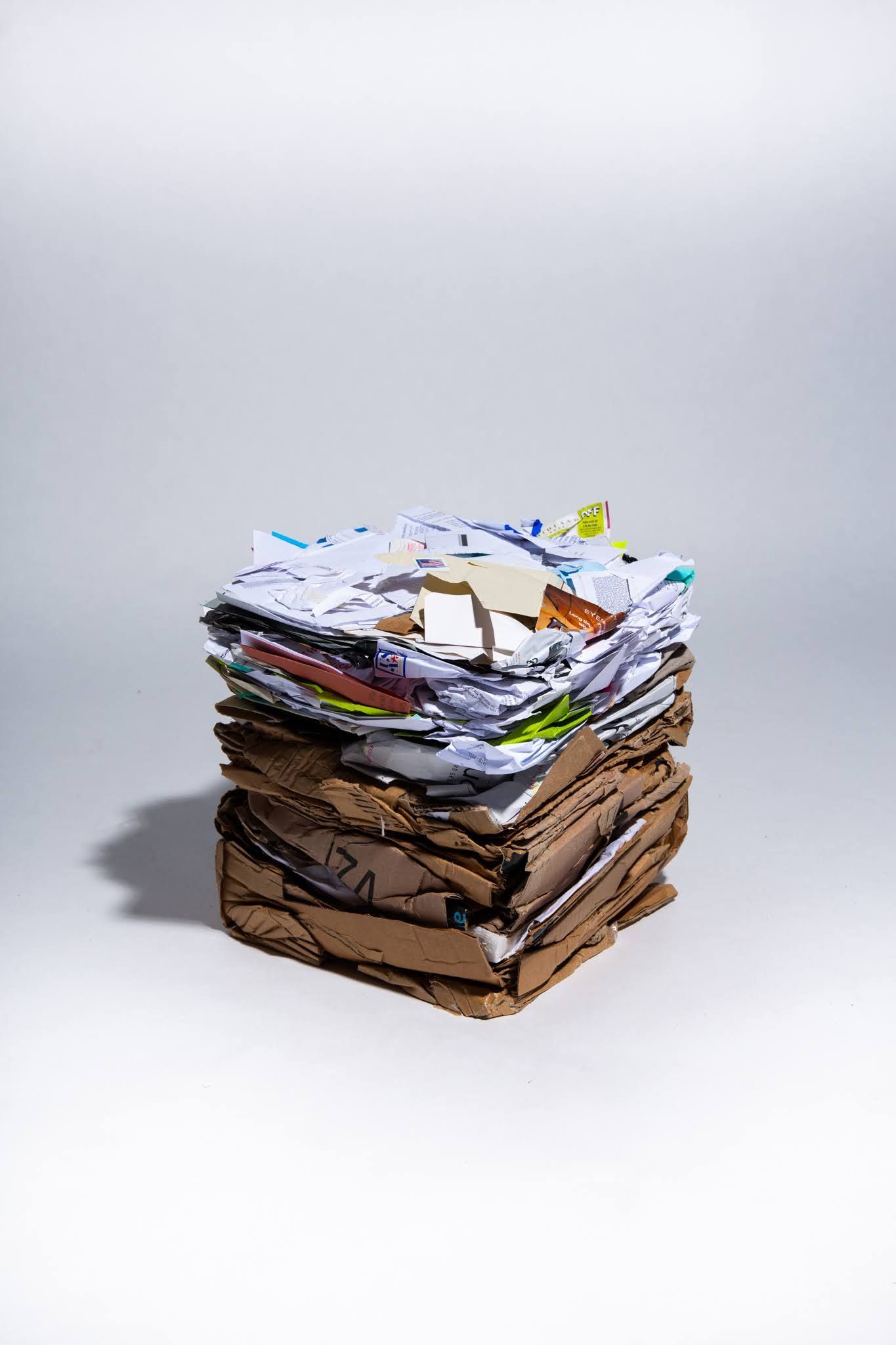 Stack of mixed paper and cardboard on white background; art by Matt Remsbecher. 