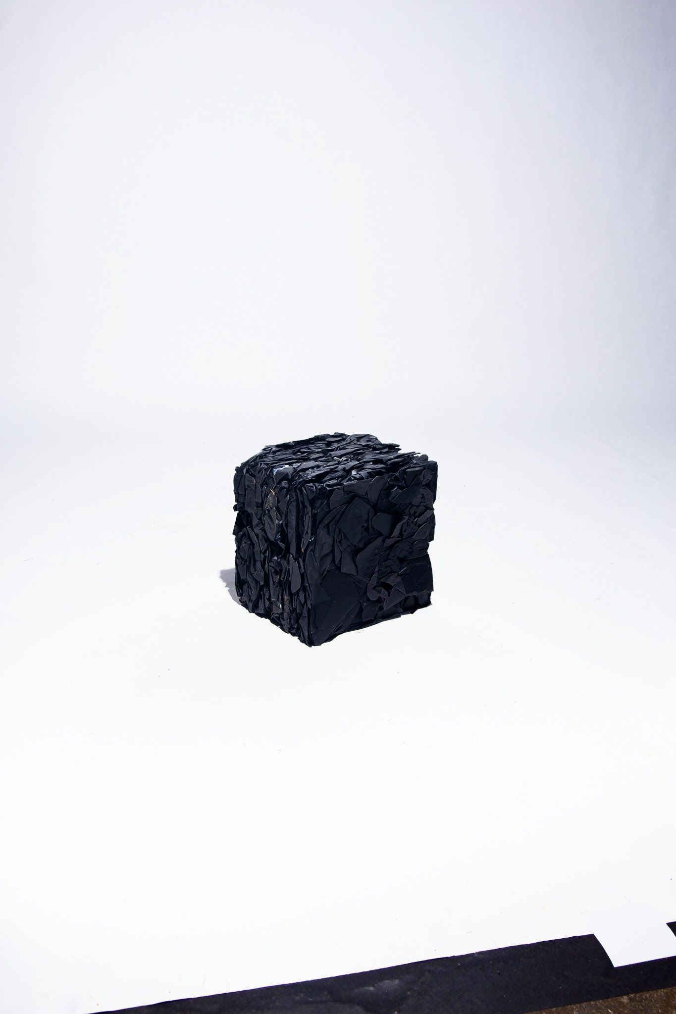 Black, textured cube against a white background; art by Matt Remsbecher. 