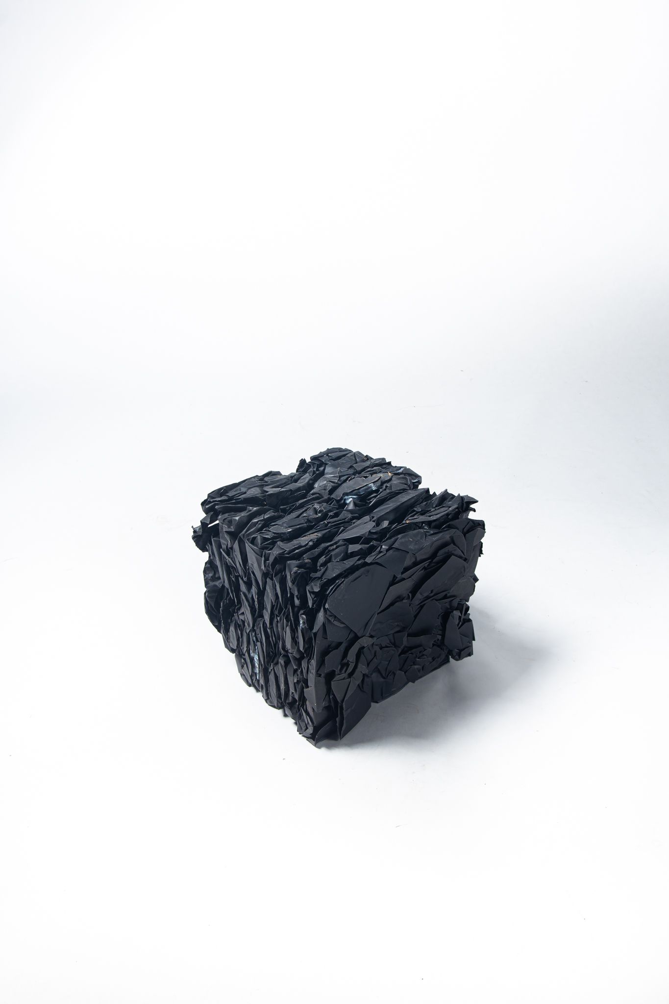 Black, textured, cube-shaped object on a white background; art by Matt Remsbecher. 