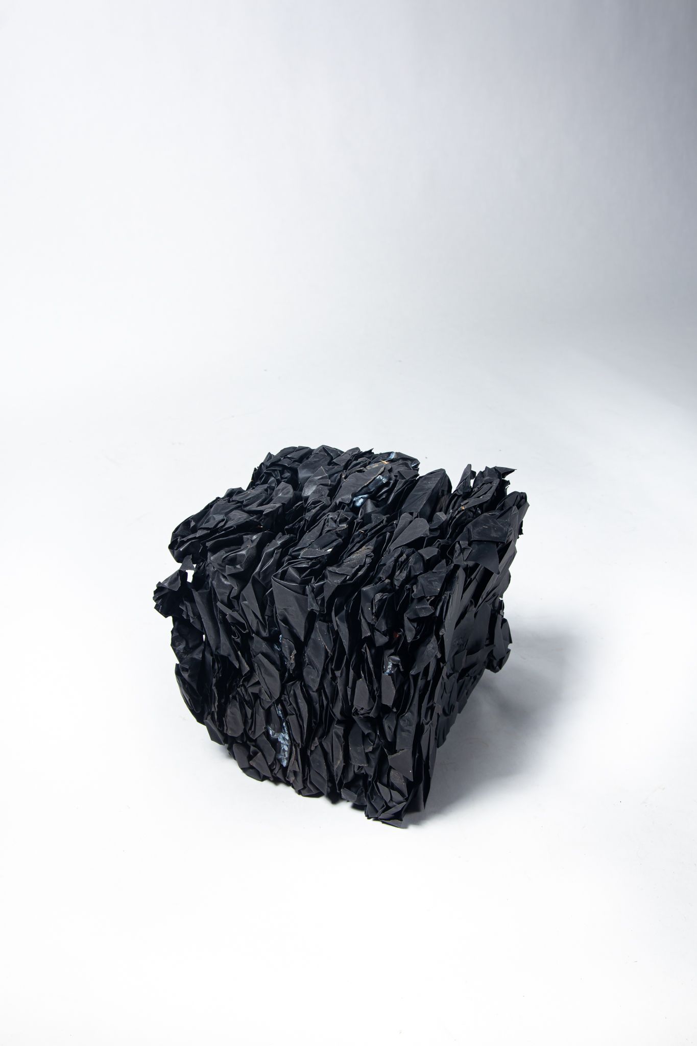 Black, textured, cube-shaped object on a white background; art by Matt Remsbecher. 