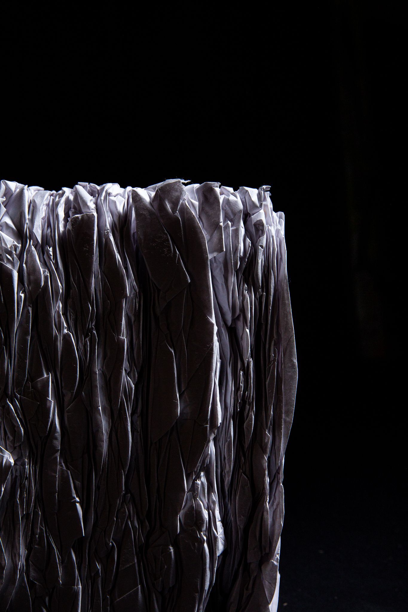 Abstract dark gray block with textured, uneven surface, against a black background; art by Matt Remsbecher. 