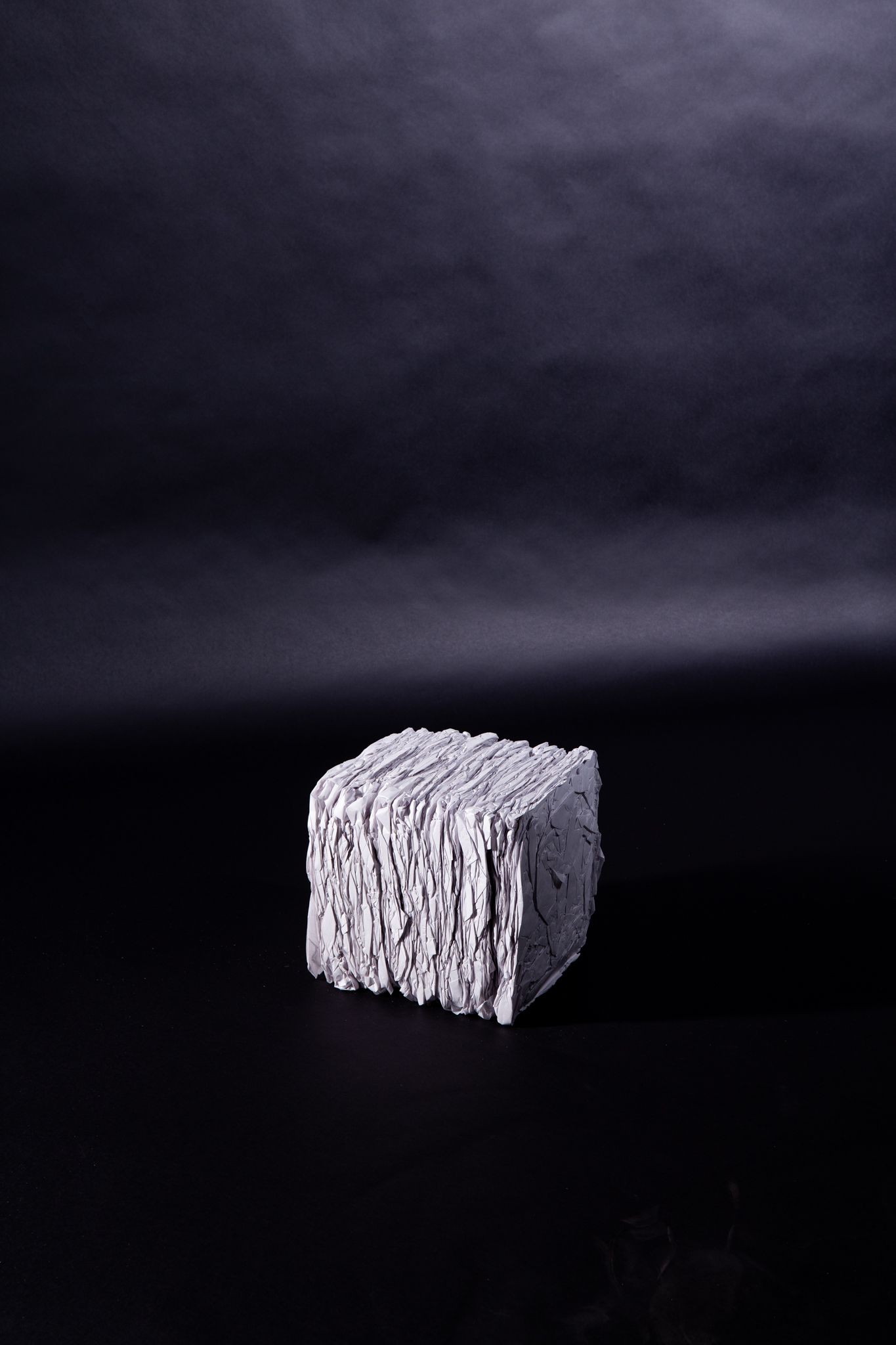 Gray, textured cube on black background; art by Matt Remsbecher. 