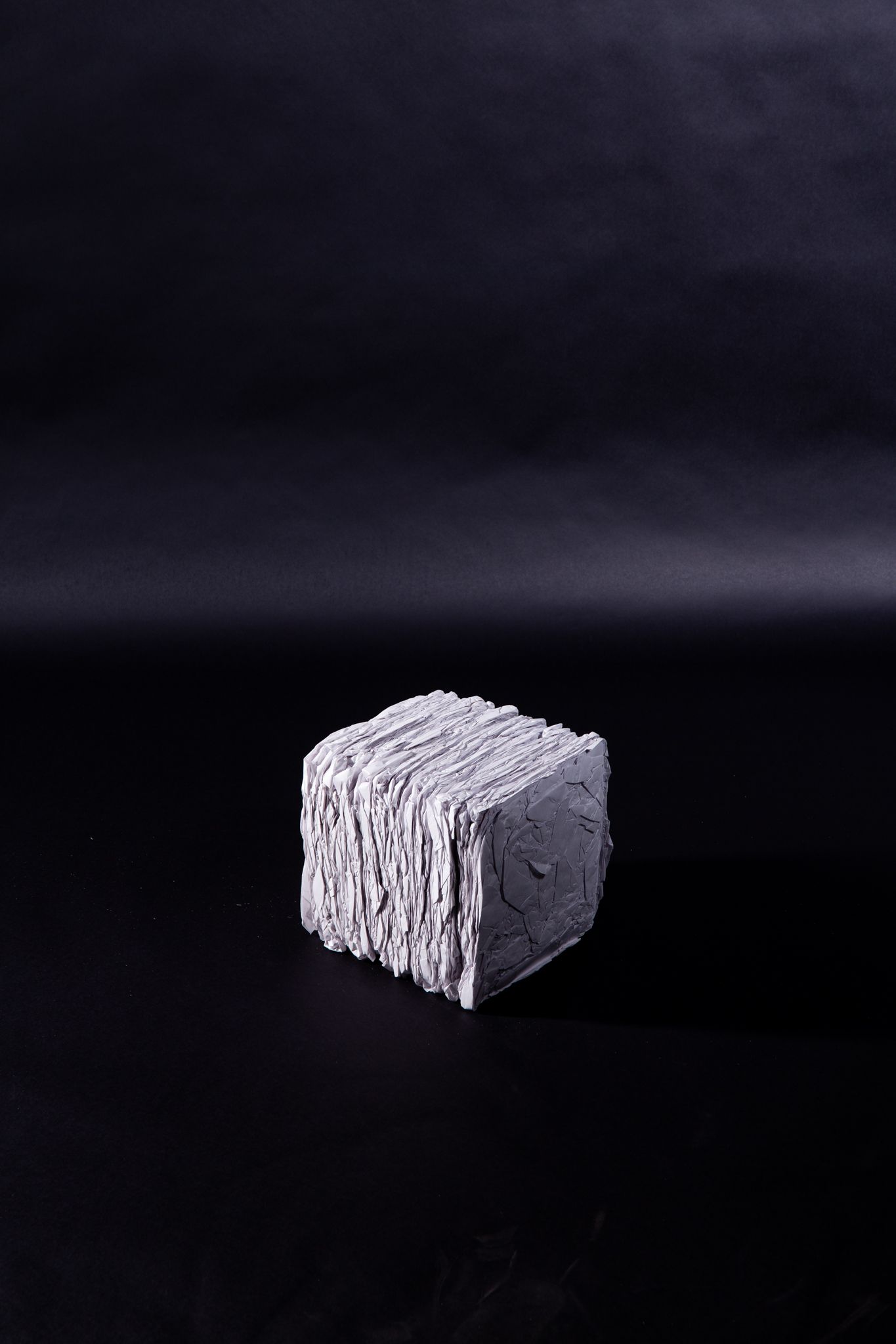 A small, textured, silver cube on a black background; art by Matt Remsbecher. 